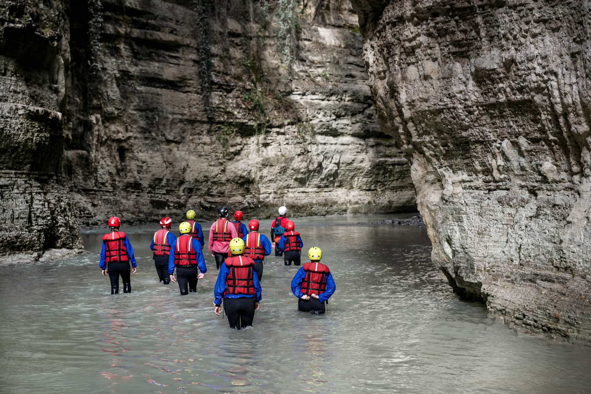 Hikers wading into the Osumi River Canyon in Albania.