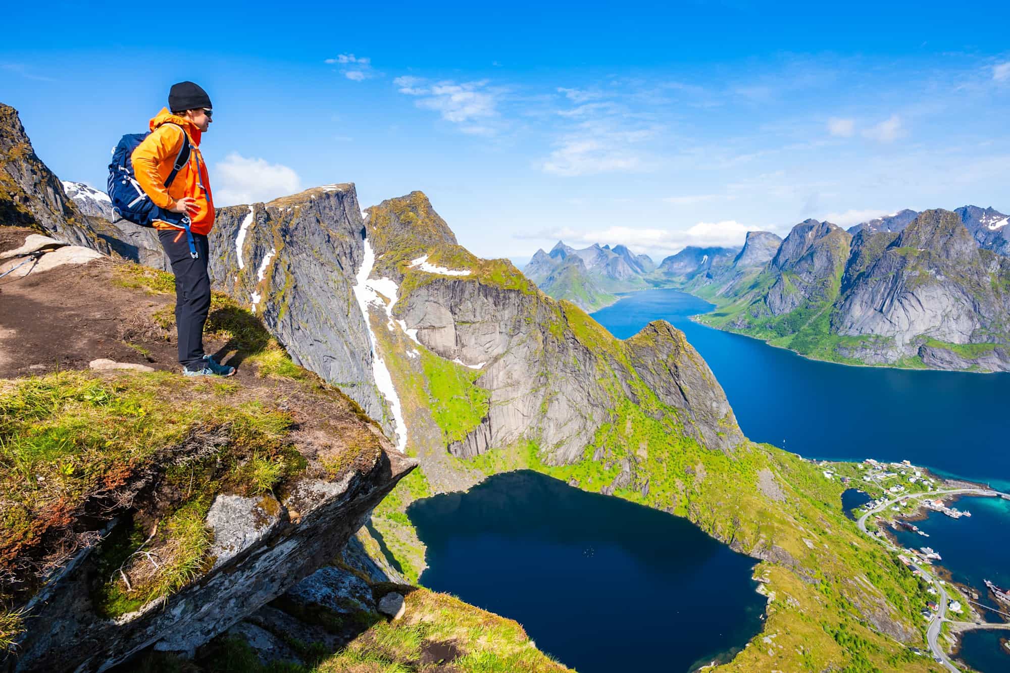 Female hiker enjoys spectacular view over mountains and fjords from Reinebringen, Lofoten Islands, Norway