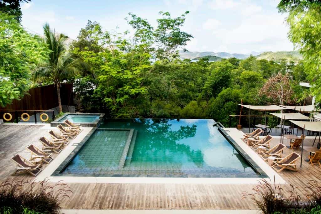Outdoor pool with lounge chairs looking onto a forest garden