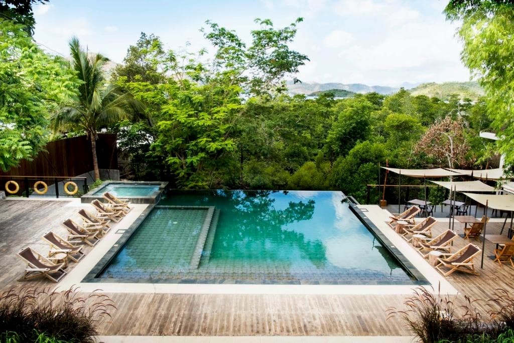 Outdoor pool with lounge chairs looking onto a forest garden