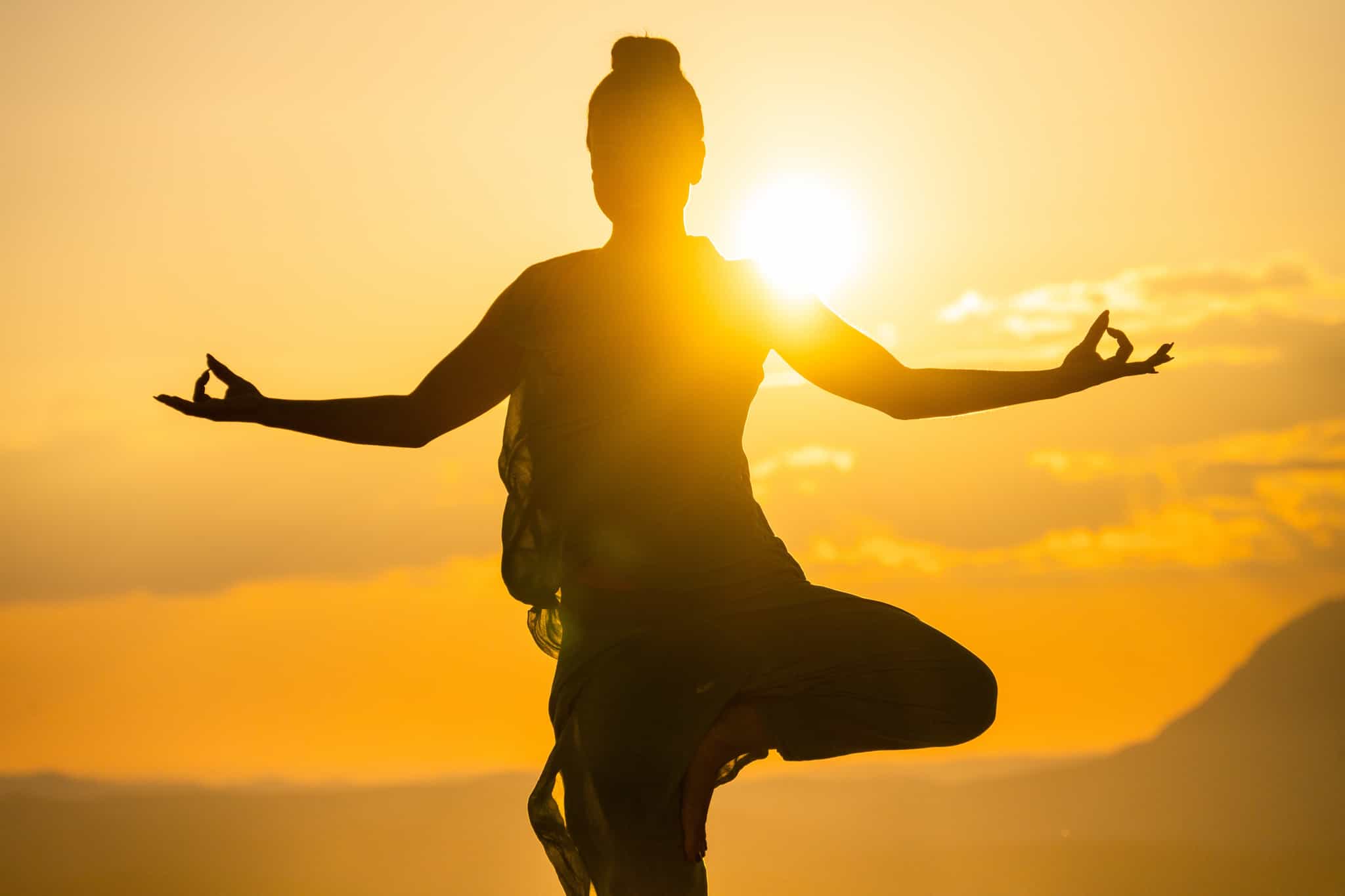 Women in yoga pose at sunrise