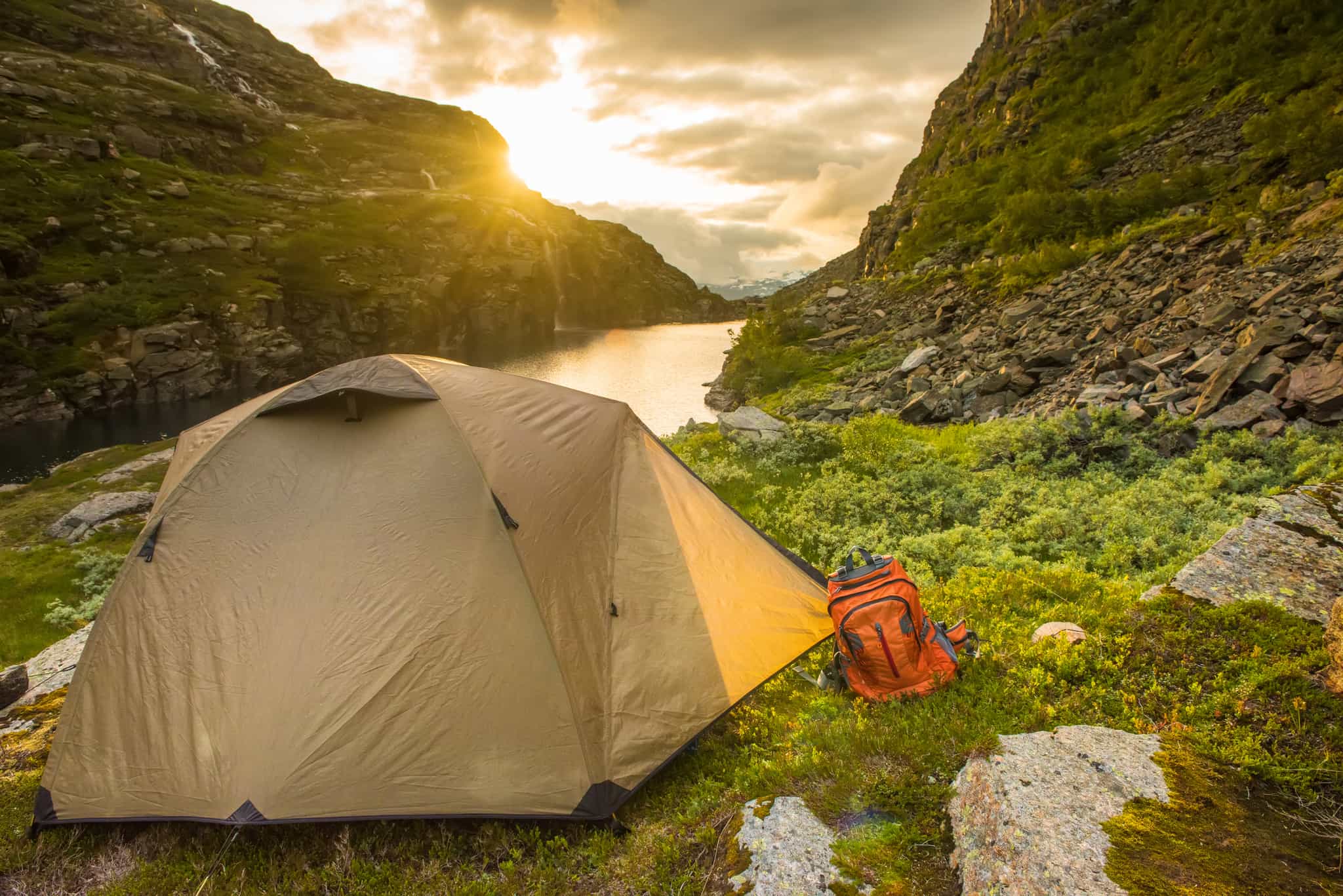 A tent on the edge of the Norwegian Fjords at sunrise.