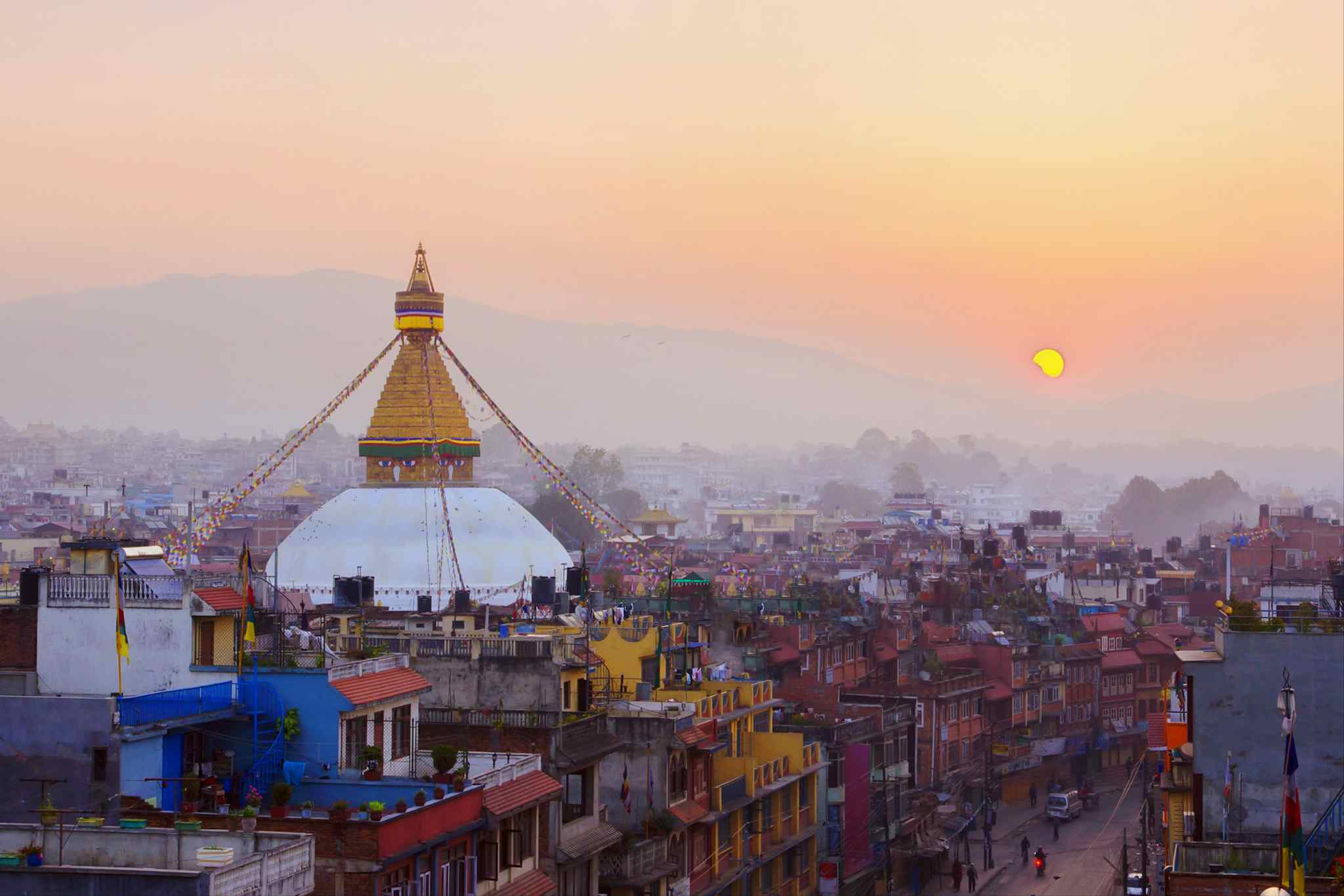 Aerial view of Kathmandu, Nepal at sunset with a stupa rising into the skyline.