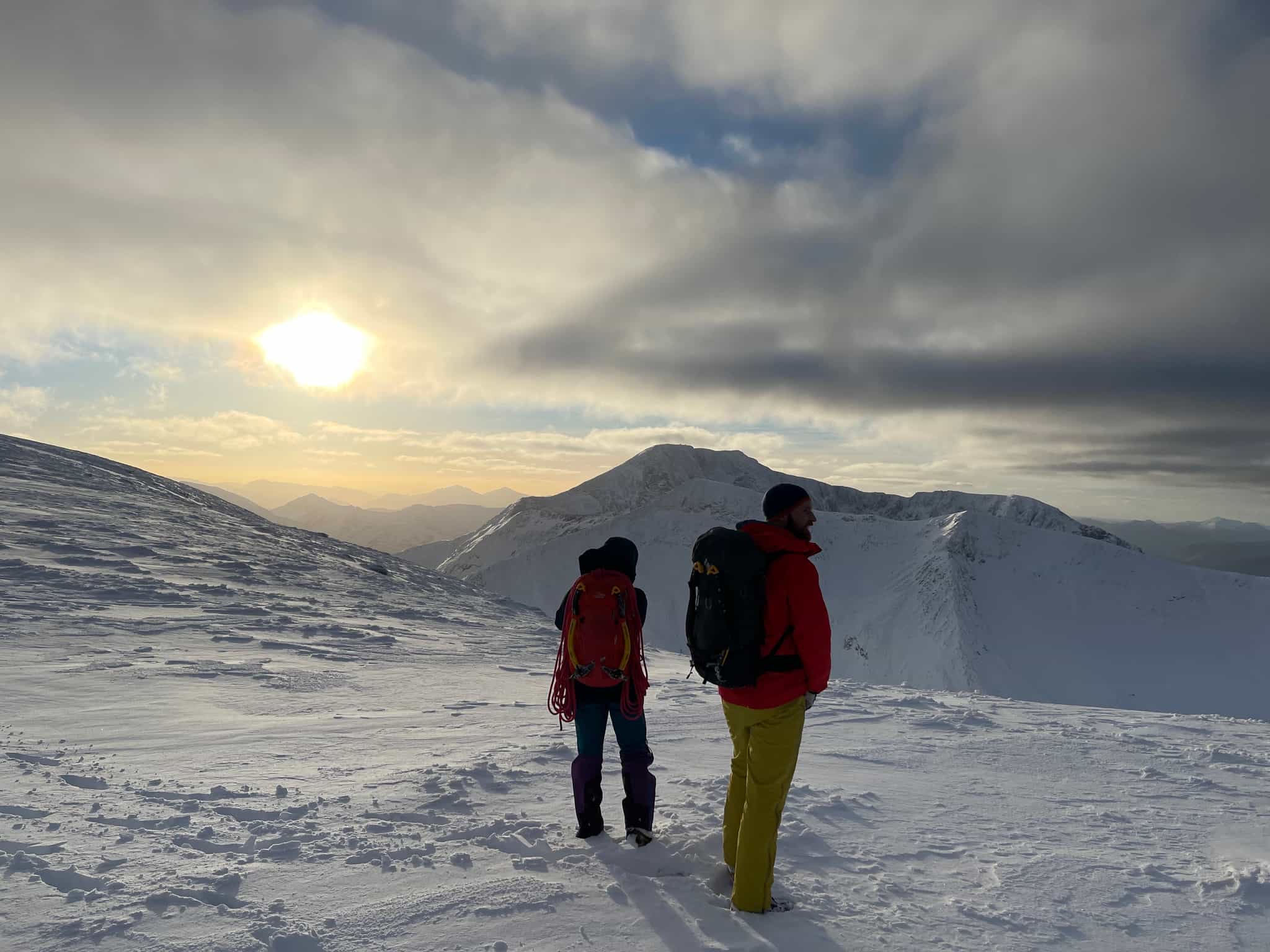Two people looking out over mountain landscapes in the snow, Ben Nevis, Scotland.