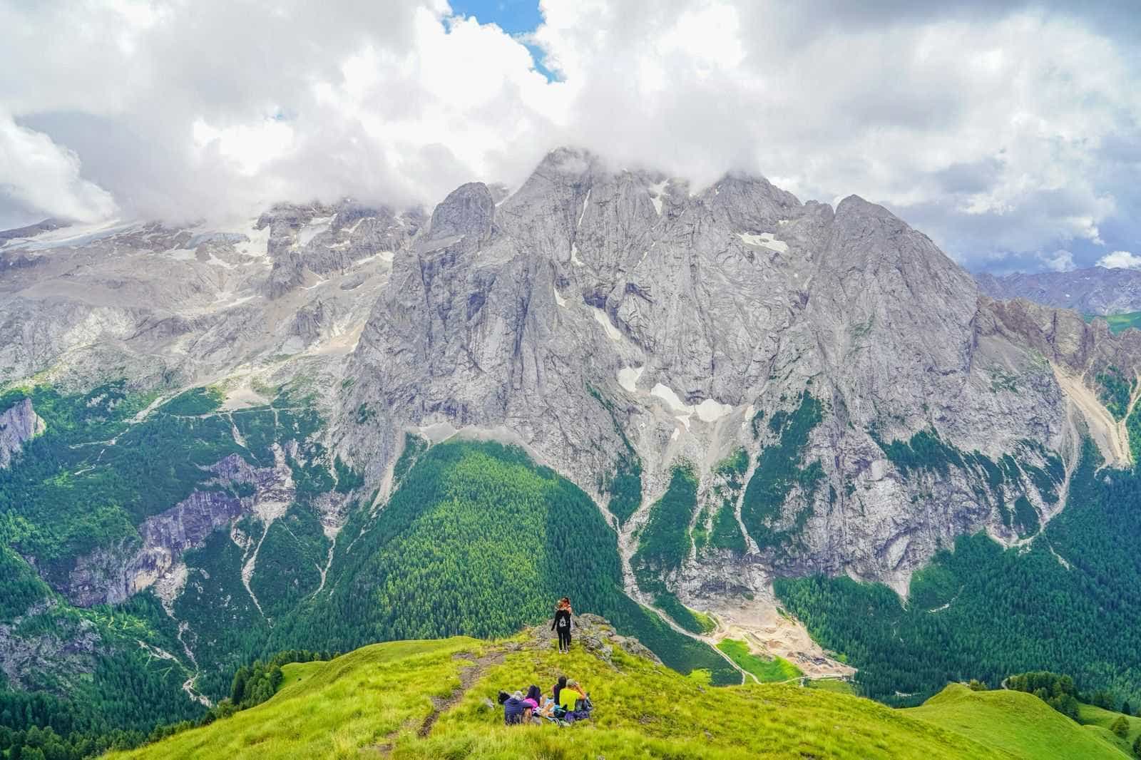 Group of hikers resting below views of Viel del Pan in the Italian Dolomites