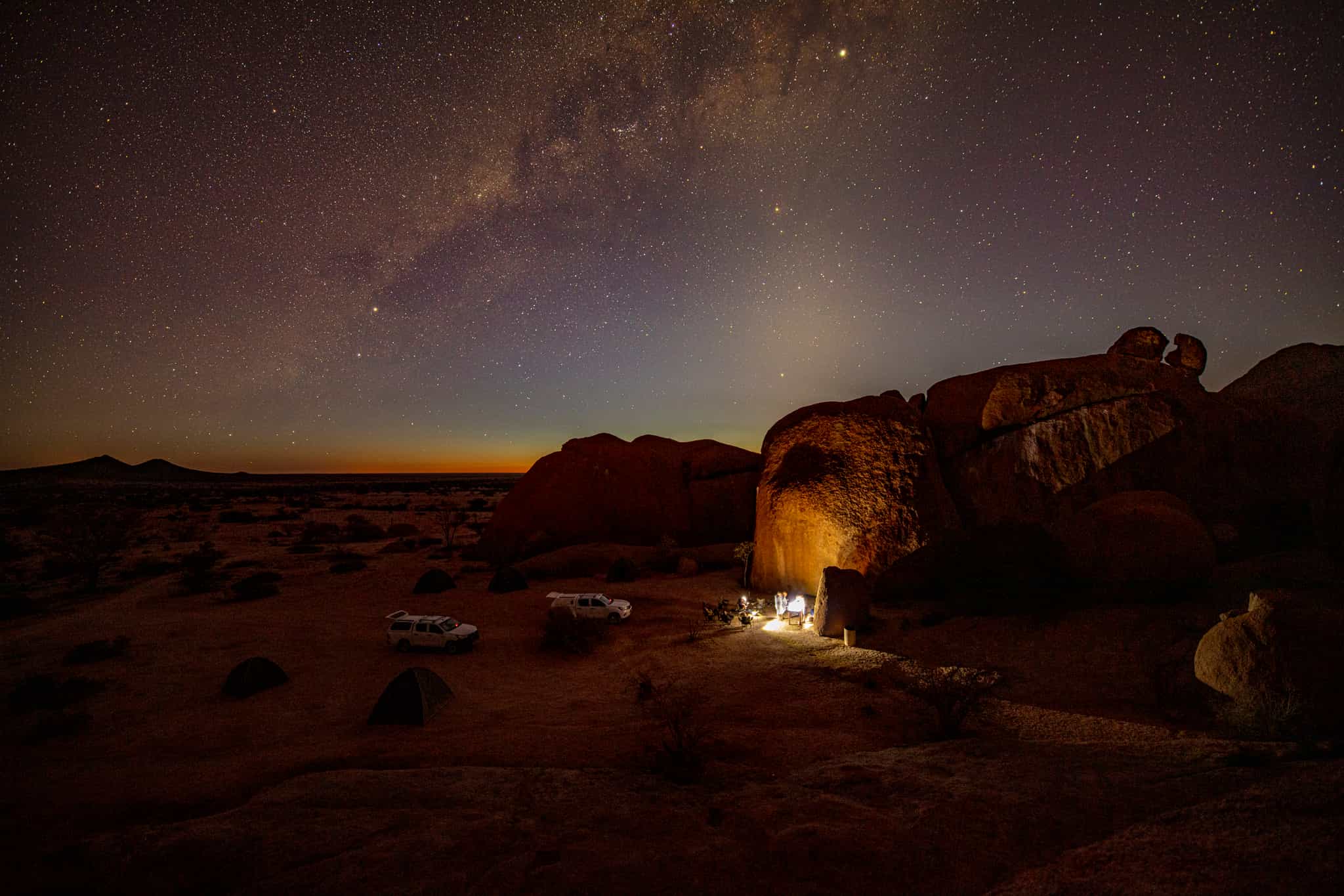 Vehicles camped in the Namib Desert at night with starry skies above