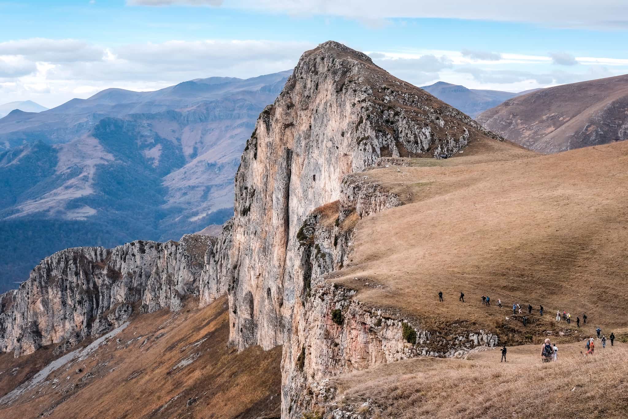 A group of tourists climbing up Mount Dimats on cloudy autumn day. Dilijan National Park, Tavush Province, Armenia.
