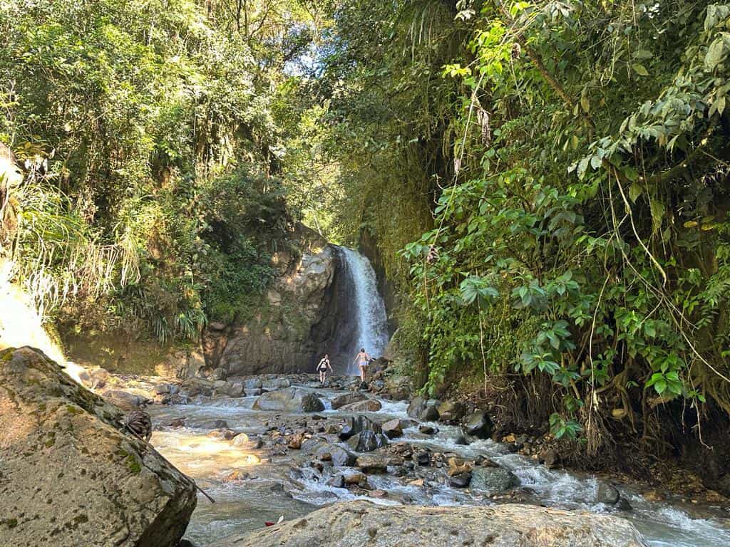 Two people approaching a pristine waterfall in the forest, Costa Rica.