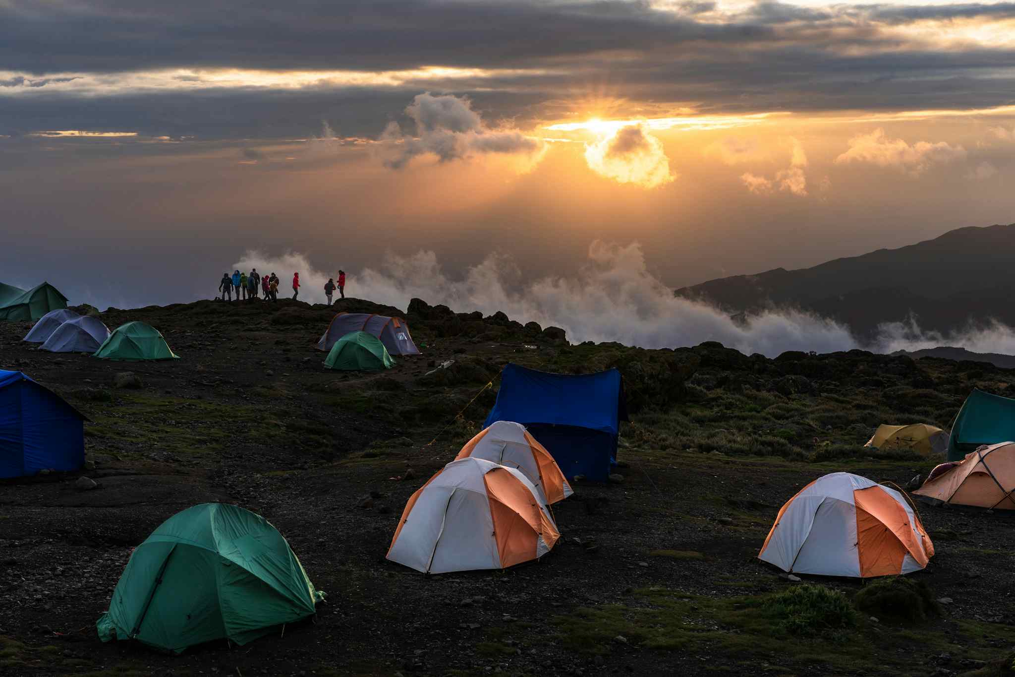 People watching the sun set from Shira Camp, Kilimanjaro, with tents in the foreground.