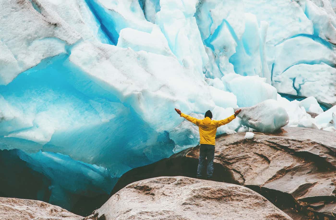 A male hiker stands in front of the Styggebreen Glacier, Norway. 
