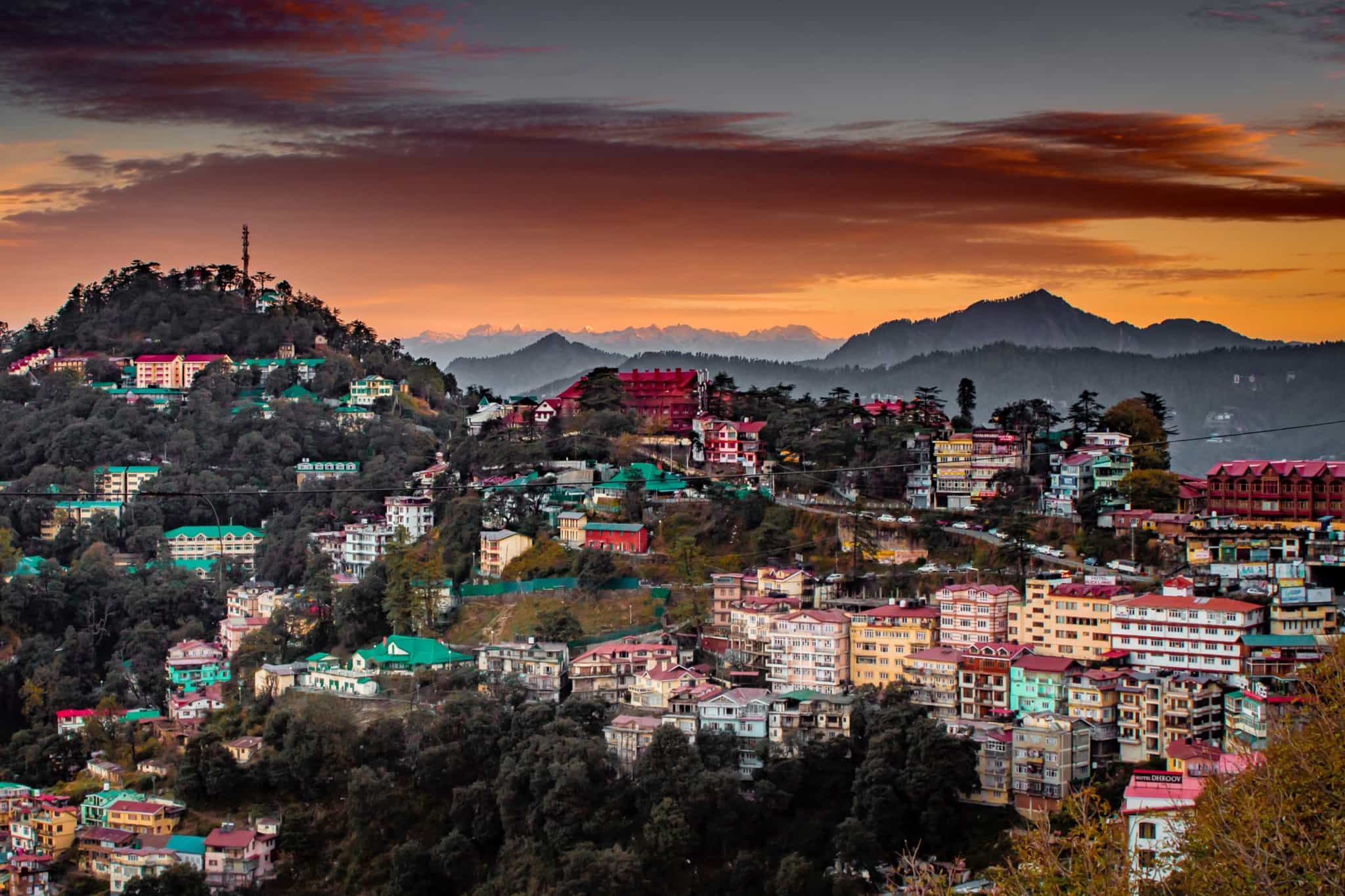 Aerial view of Shimla, India at sunset with hills and forest in the background