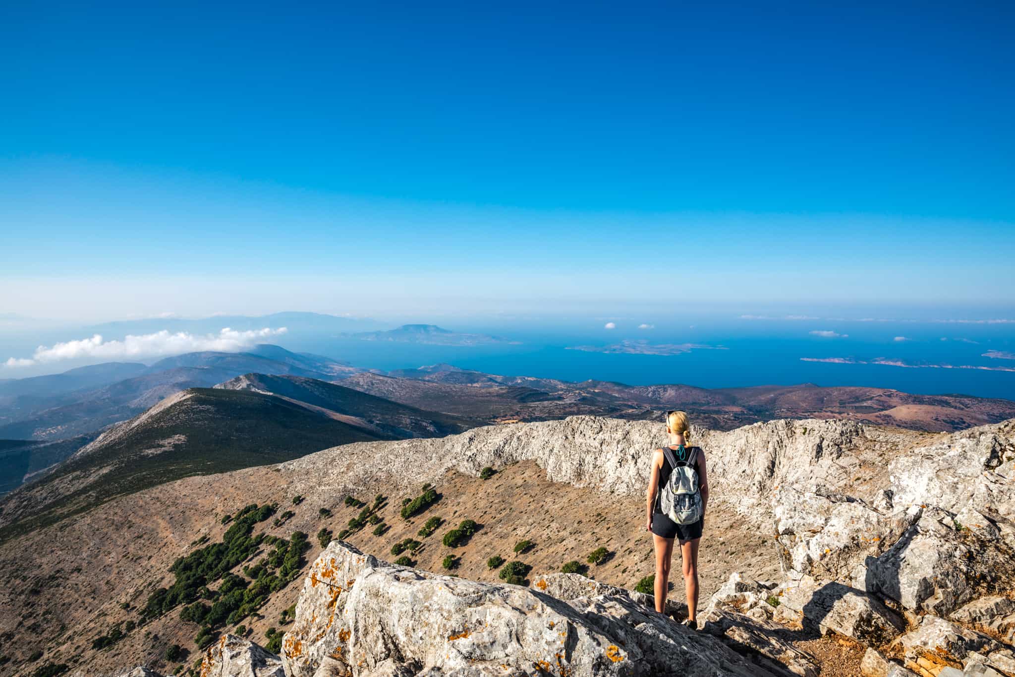 CANVA - Hiker at the summit of Mount Zas on Nazos in the Cyclades Islands, Greece. Photo: Canva link: https://www.canva.com/photos/MAEI-ybH_Ho-on-top-of-mount-zas/