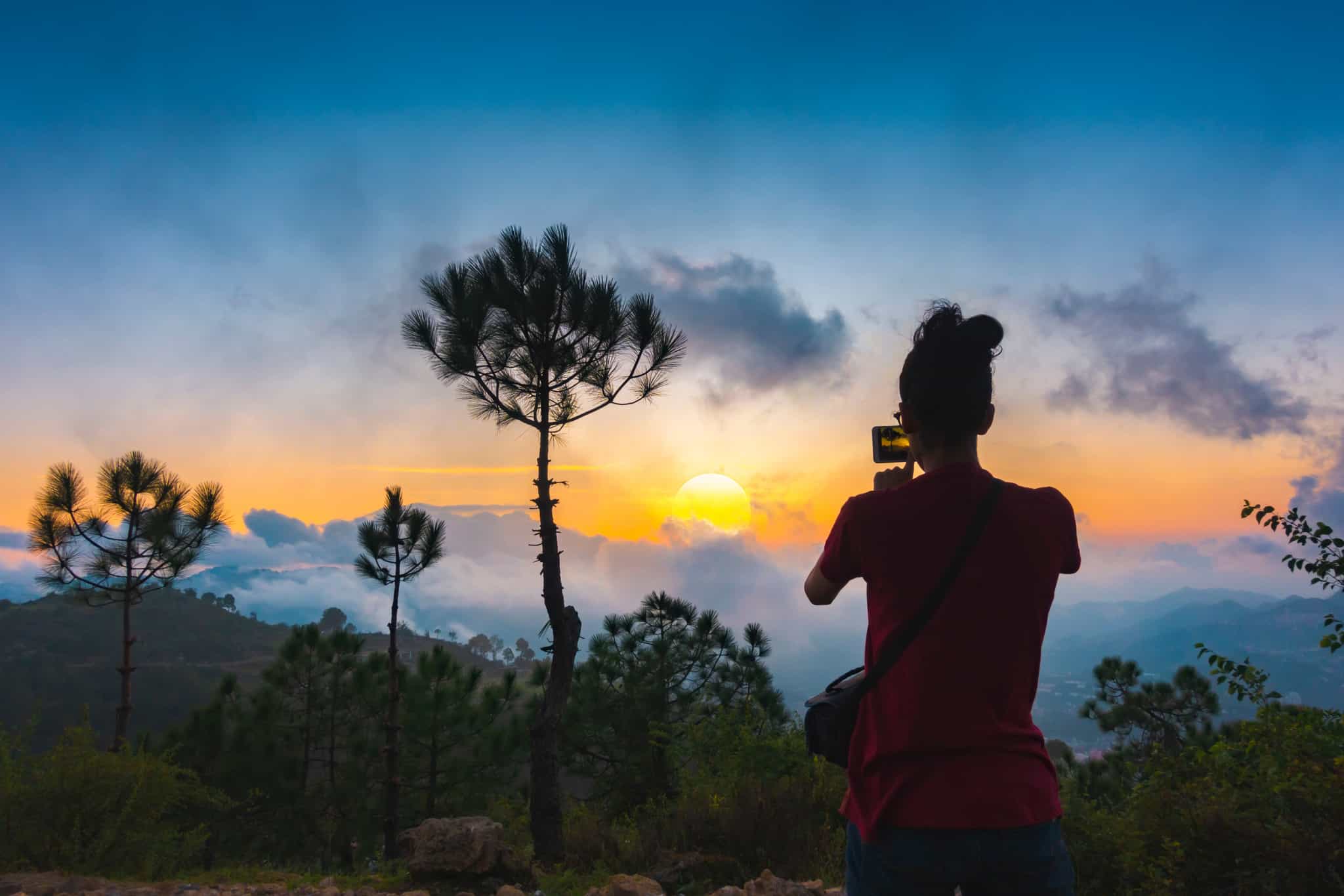 Women takes photo of the sunset from a mountain viewpoint