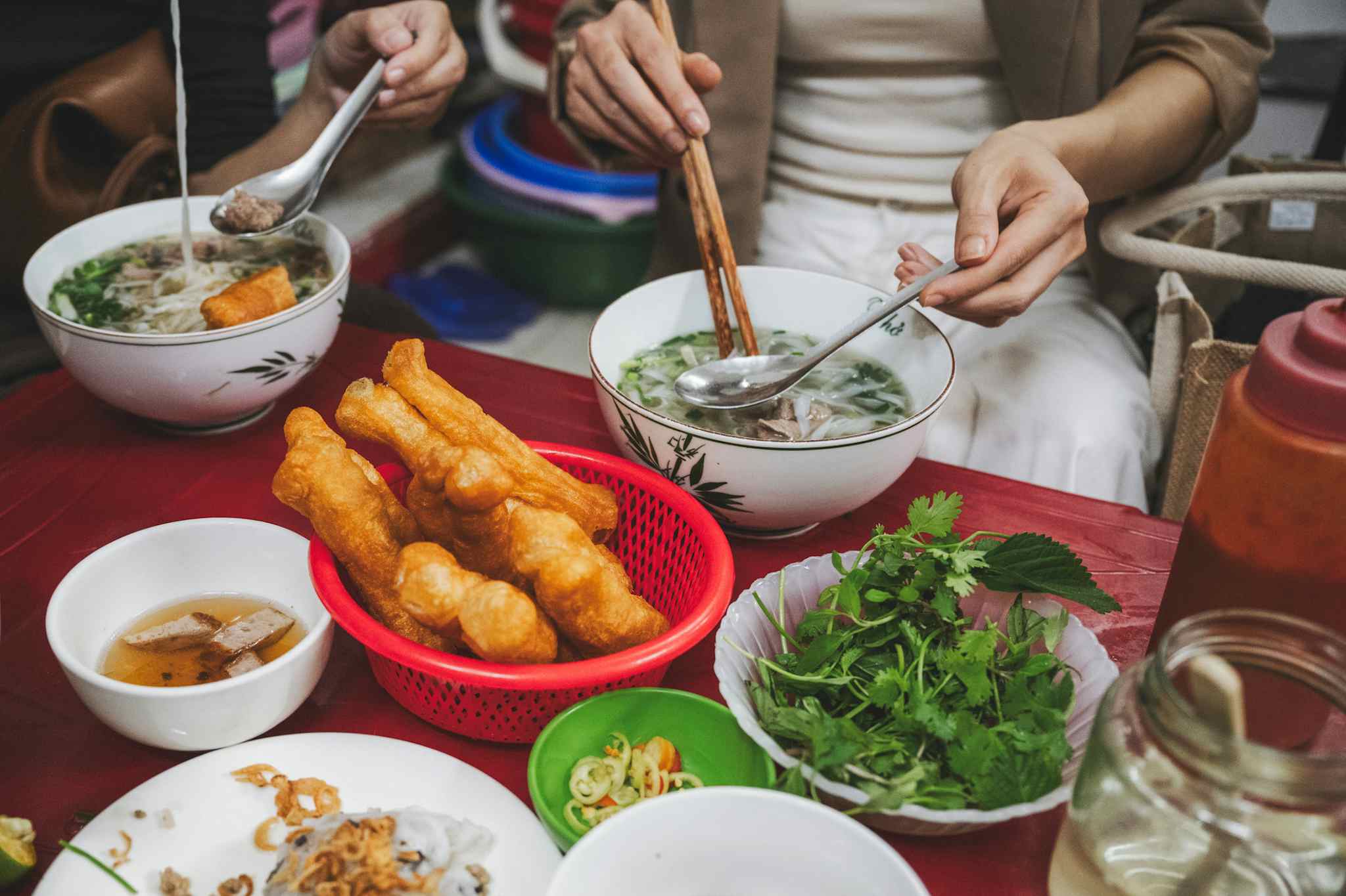 GETTY - Vietnamese woman eating pho soup with fried breadstick in street restaurant. Photo: Getty # 1466660314

