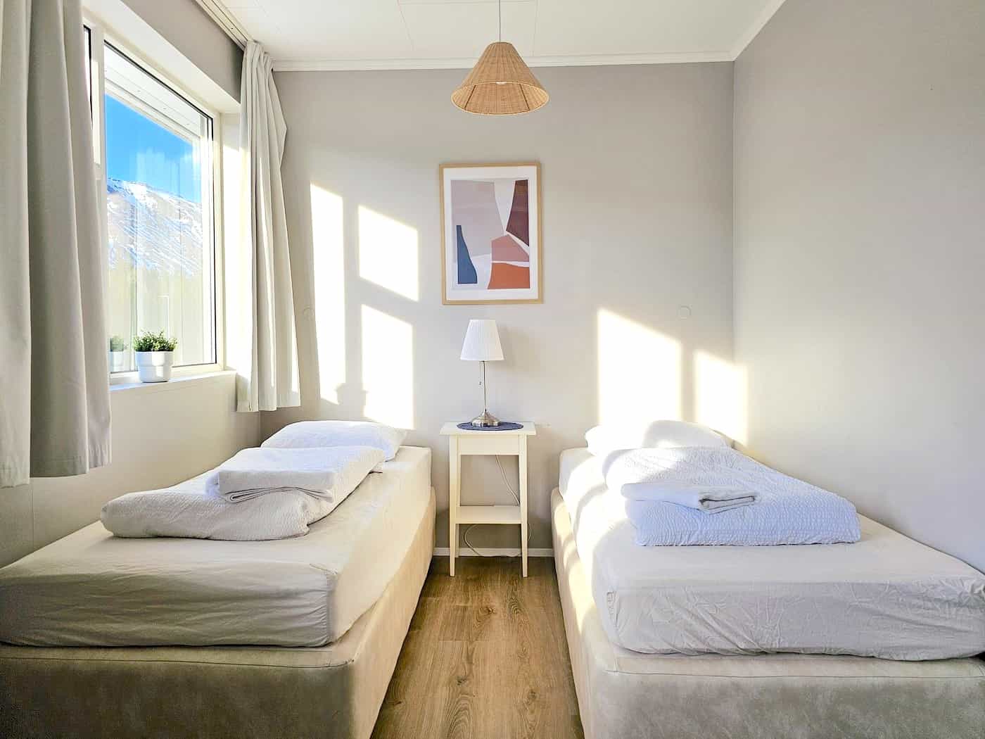 Clean, white bedroom with twin beds and a picture on the wall
