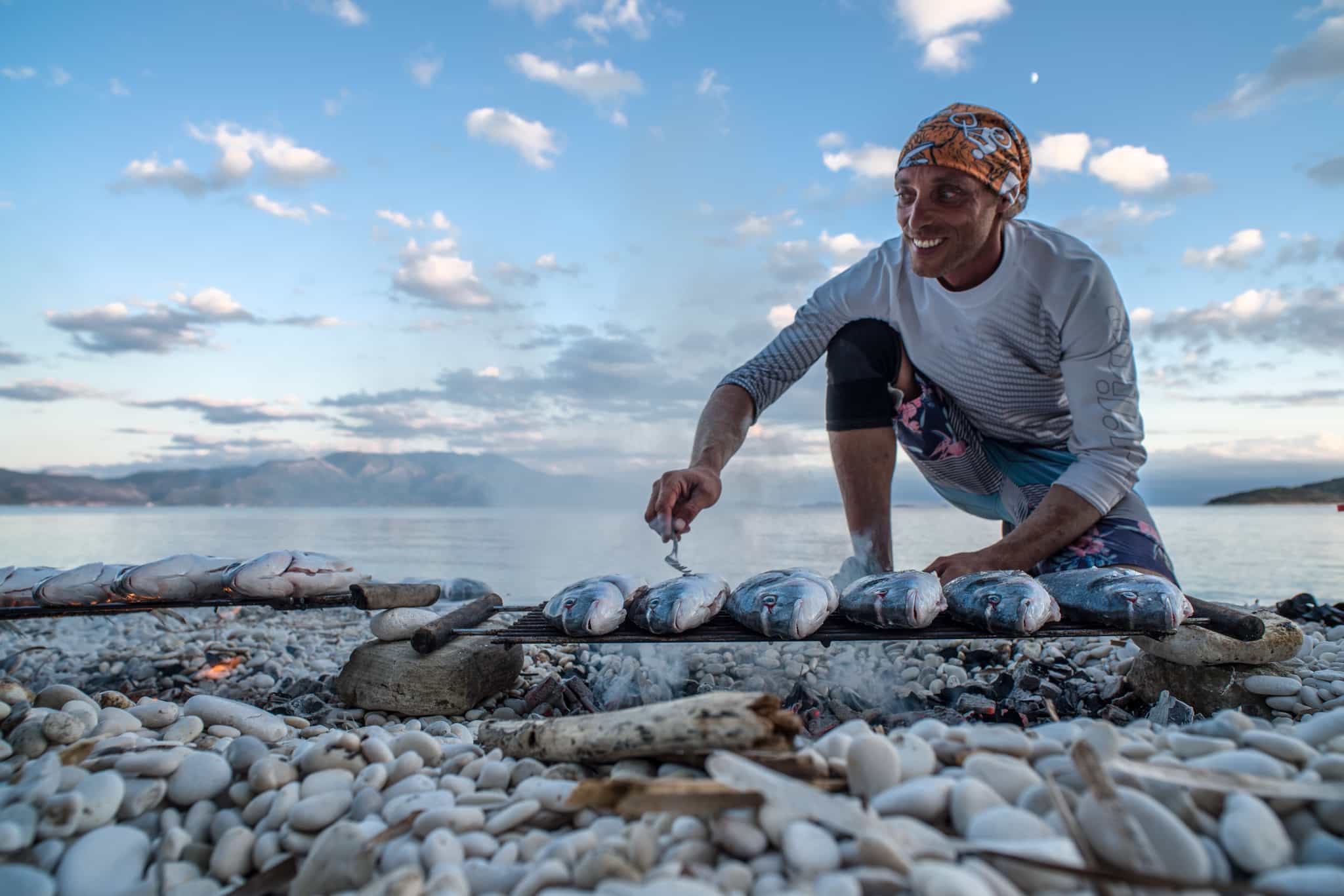 Guide cooking fresh fish over a barbeque in Greece.