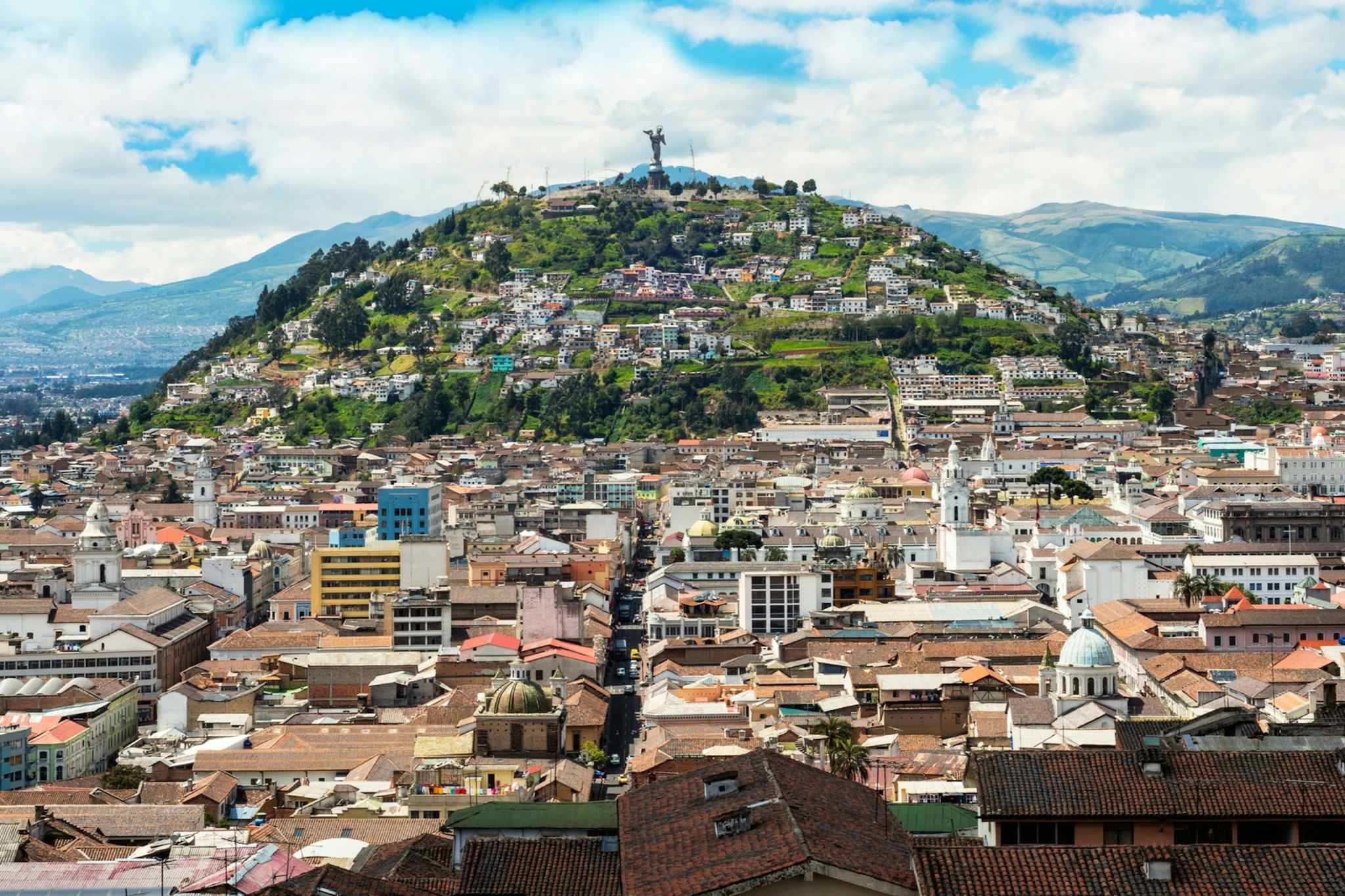 A city scape of Quito with the Virgen de El Panecillo statue standing proud in the background. 