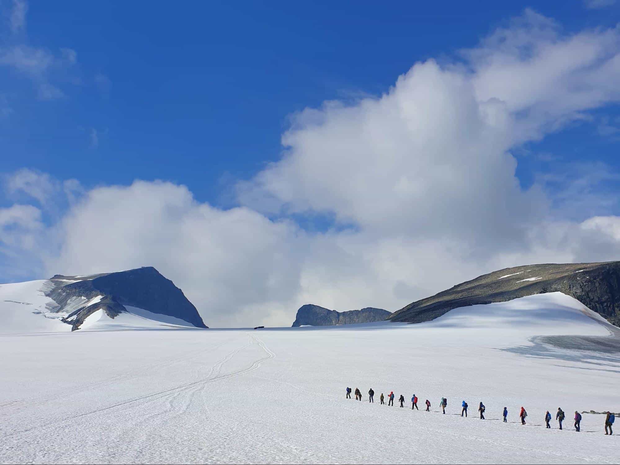 A group of hikers roped together on the snowy slops of Galdhøpiggen, the highest mountain in Norway.
