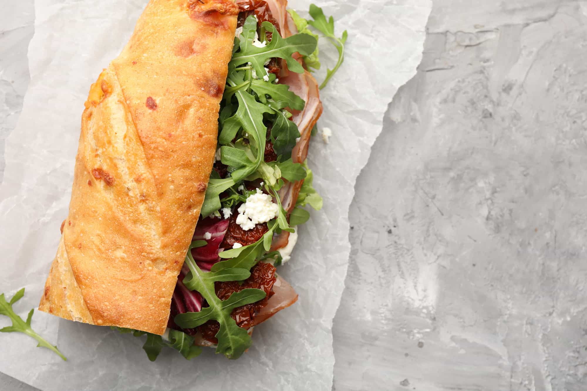 A sandwich with rocket, feta and tomatoes.