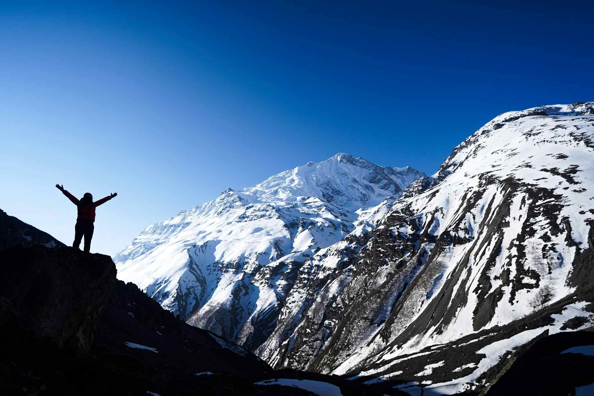 Silhouette of person with arms spread high at Tilicho Base Camp, Nepal. 
