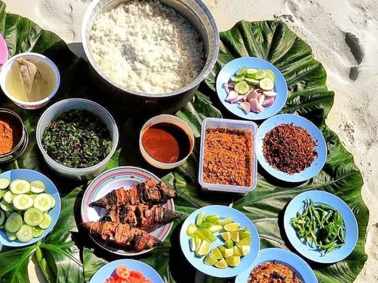 Maldivian dishes spread on palm leaves on the beach, Maldives.