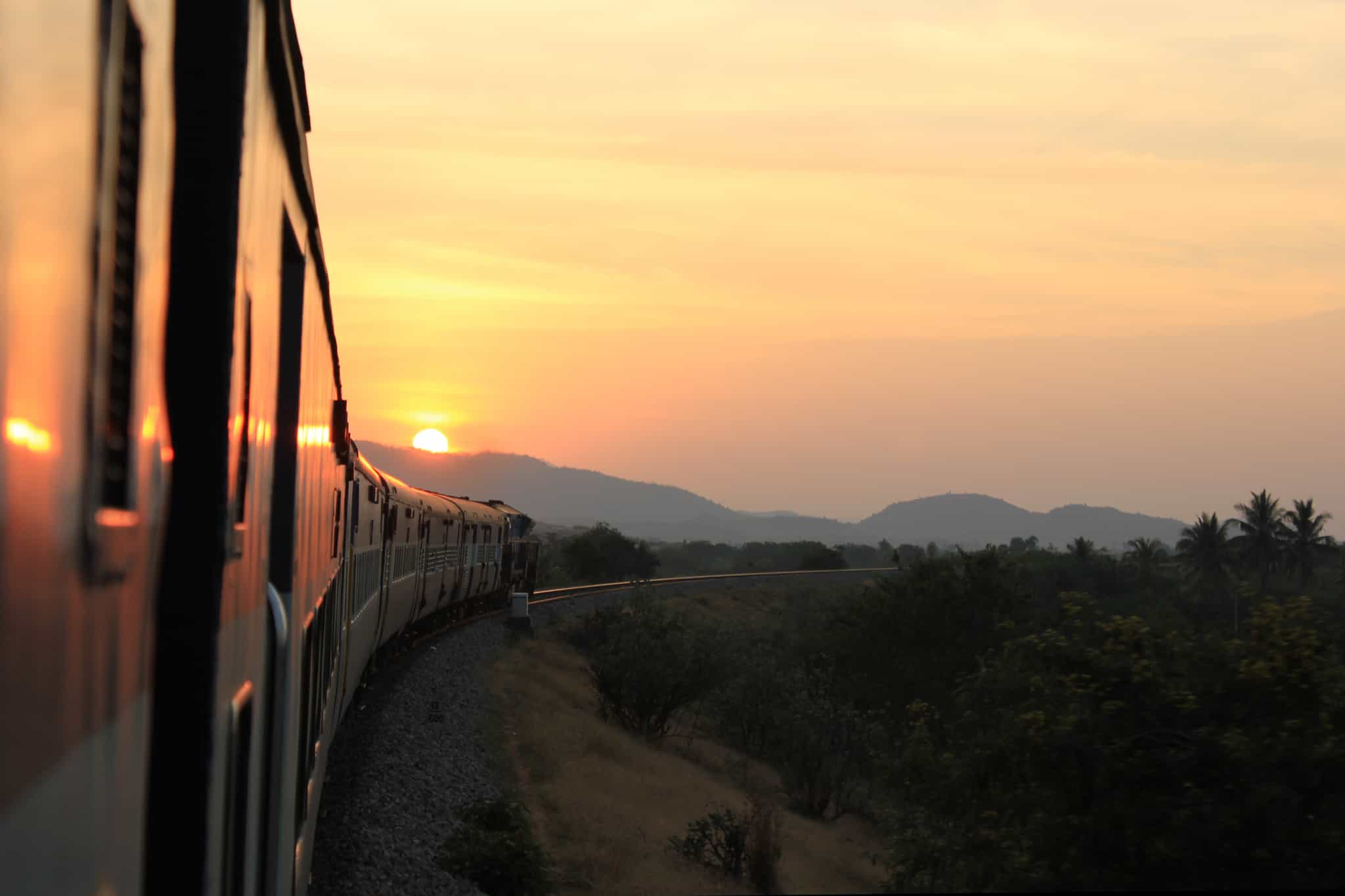 The sun setting over the mountains viewed from a train carriage. India.