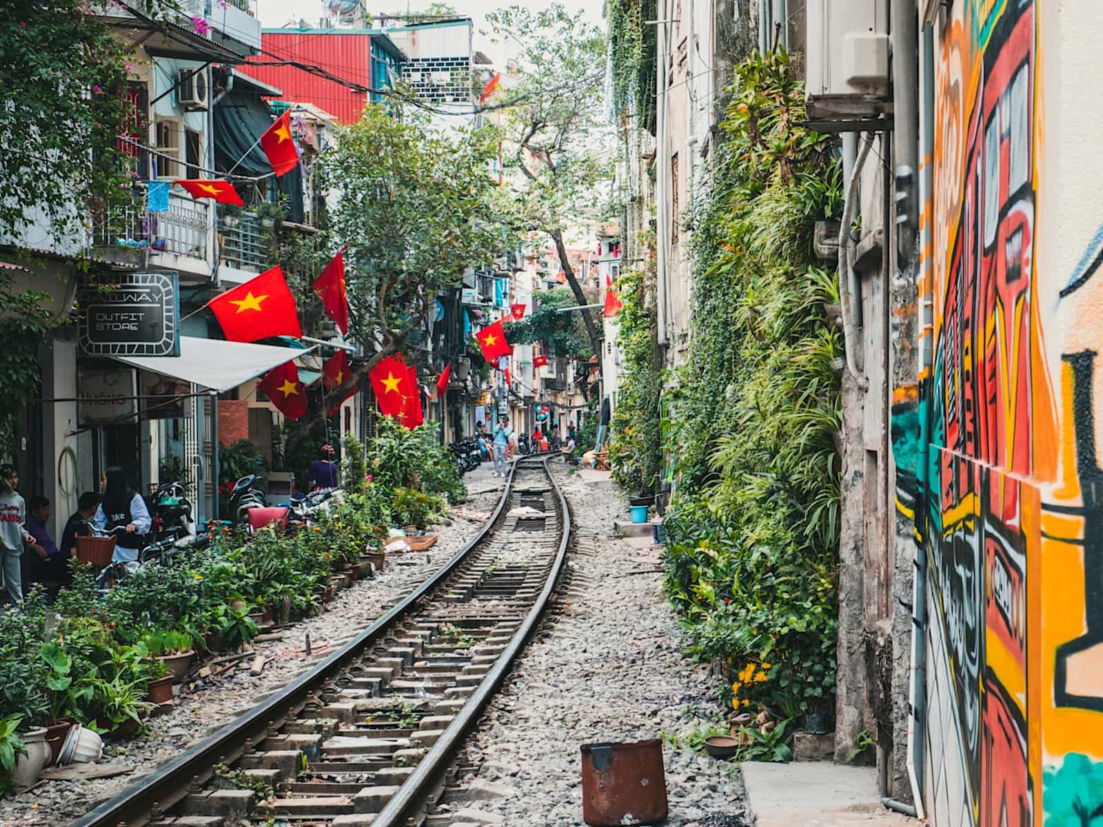 Train tracks running among buildings with Vietnamese flags, street scene in Vietnam.