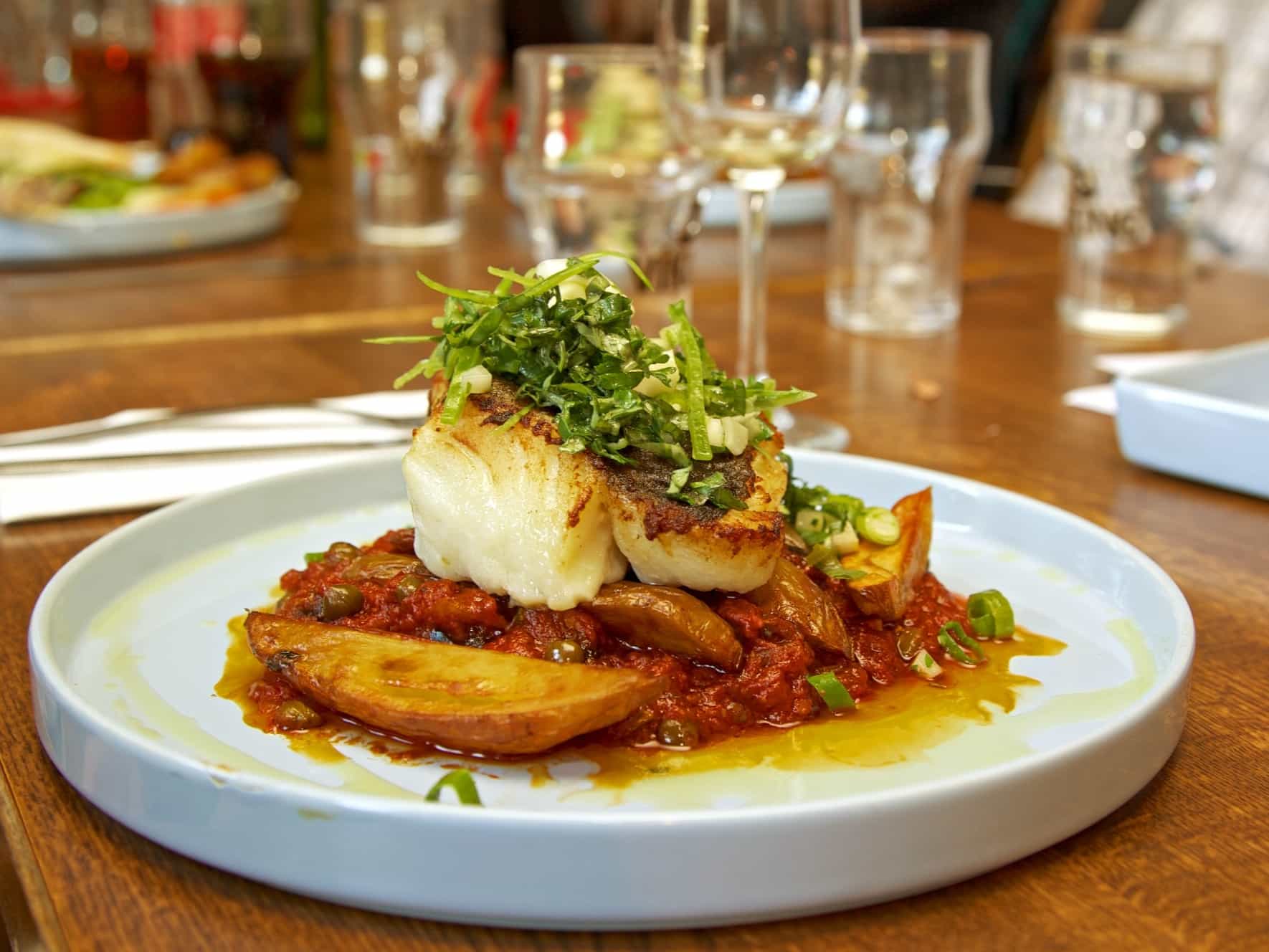 Icelandic Cod fish and tomatoes on a plate in a restaurant, Iceland.