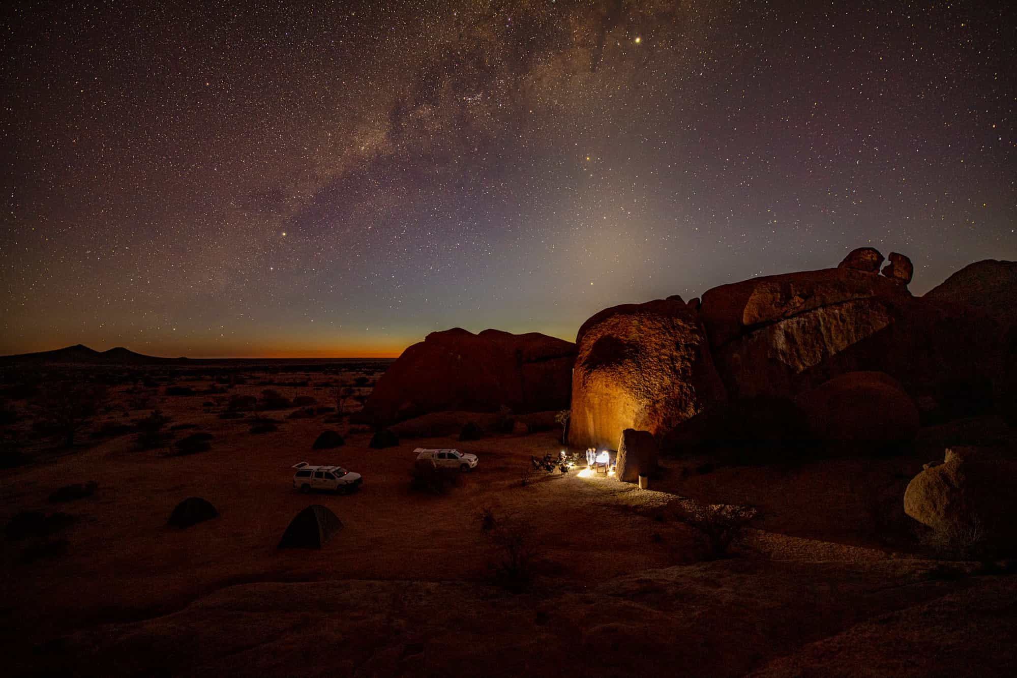 A camp in the desert of Namibia at night, with starry skies above.