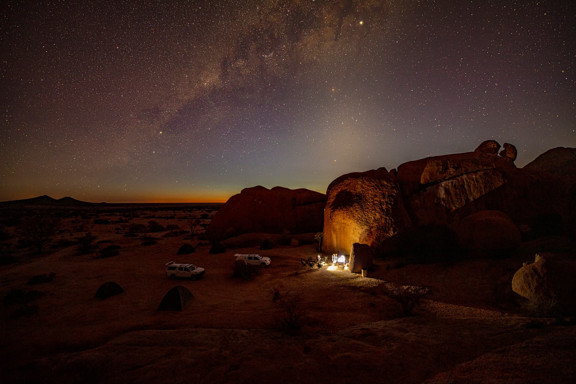 A camp in the desert of Namibia at night, with starry skies above.