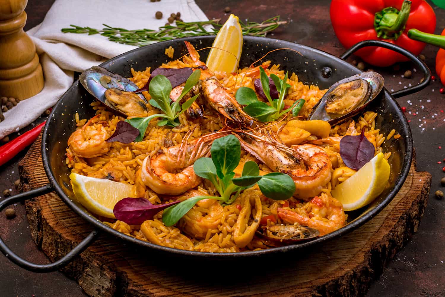 Paella with seafood topped with a green garnish and lemon slices