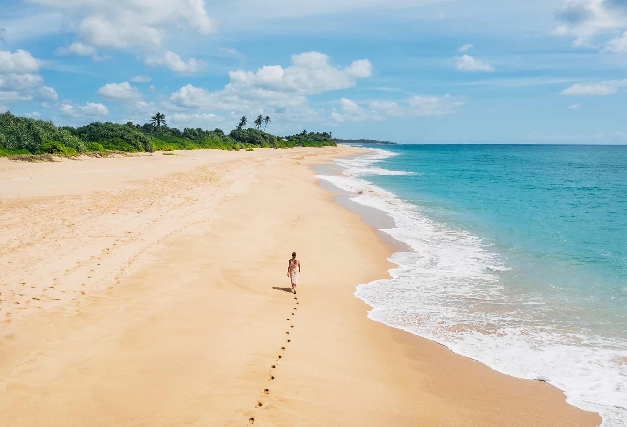 Person walking along a deserted Tangalle beach in Sri Lanka
