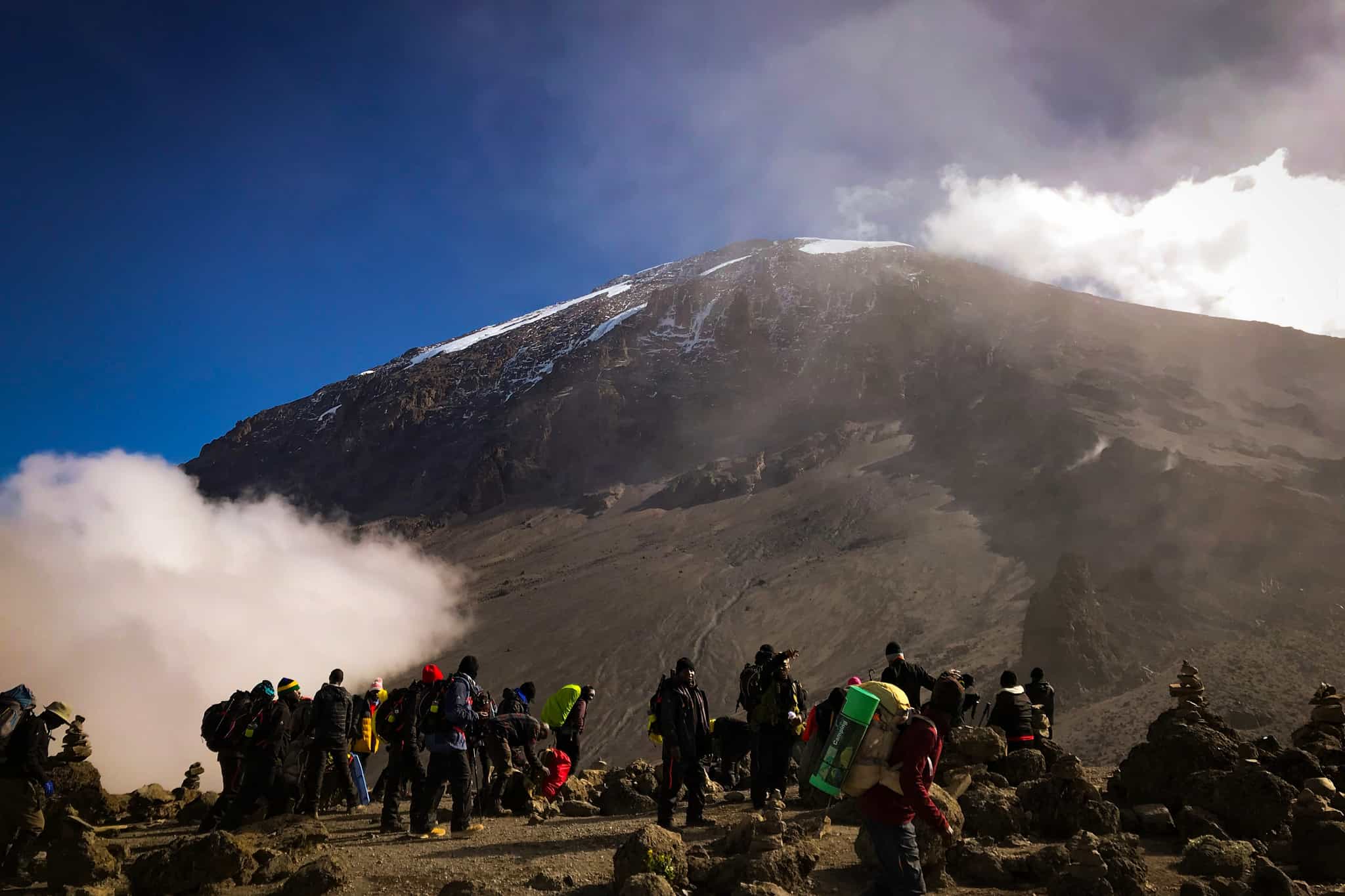 Trekkers with the looming peak of Mount Kilimanjaro in the background, Tanzania.