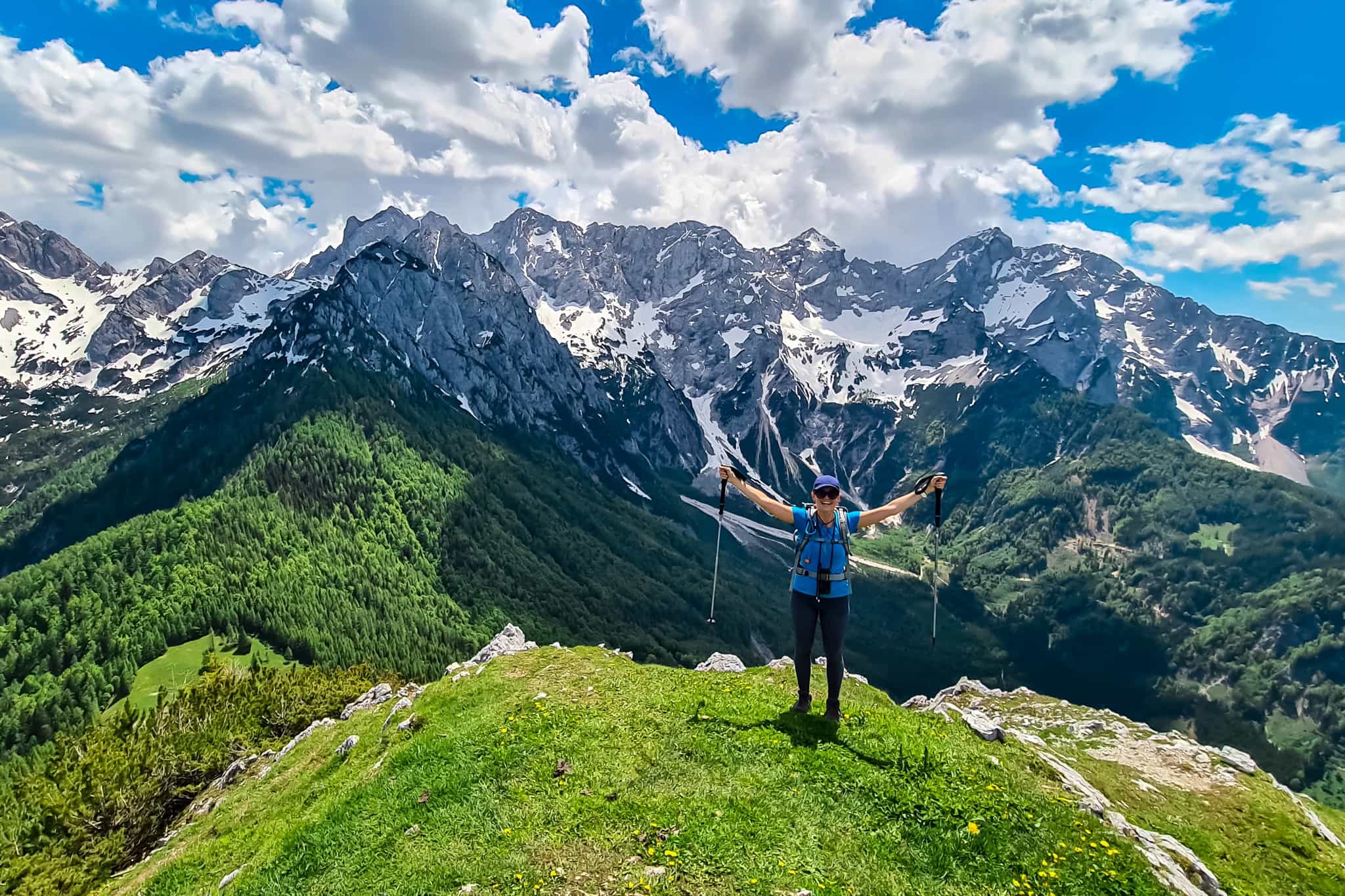 Hiker stands on top of GOli Vrh with mountain view in the background