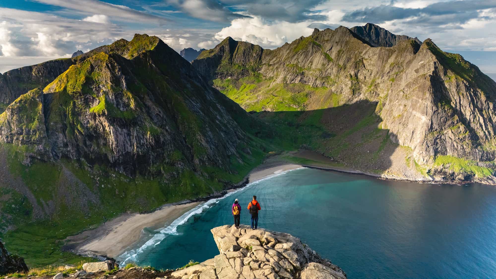Hikers overlooking Kvavlika Beach from Ryten viewpoint in the Lofoten Islands.