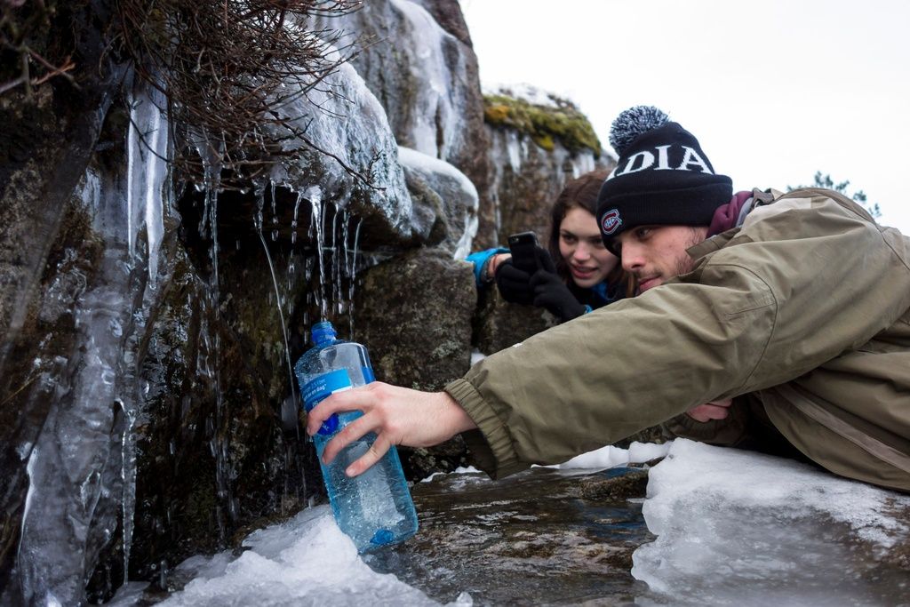 Two hikers grabbing some fresh water from the ice. This is a lot easier during summer!