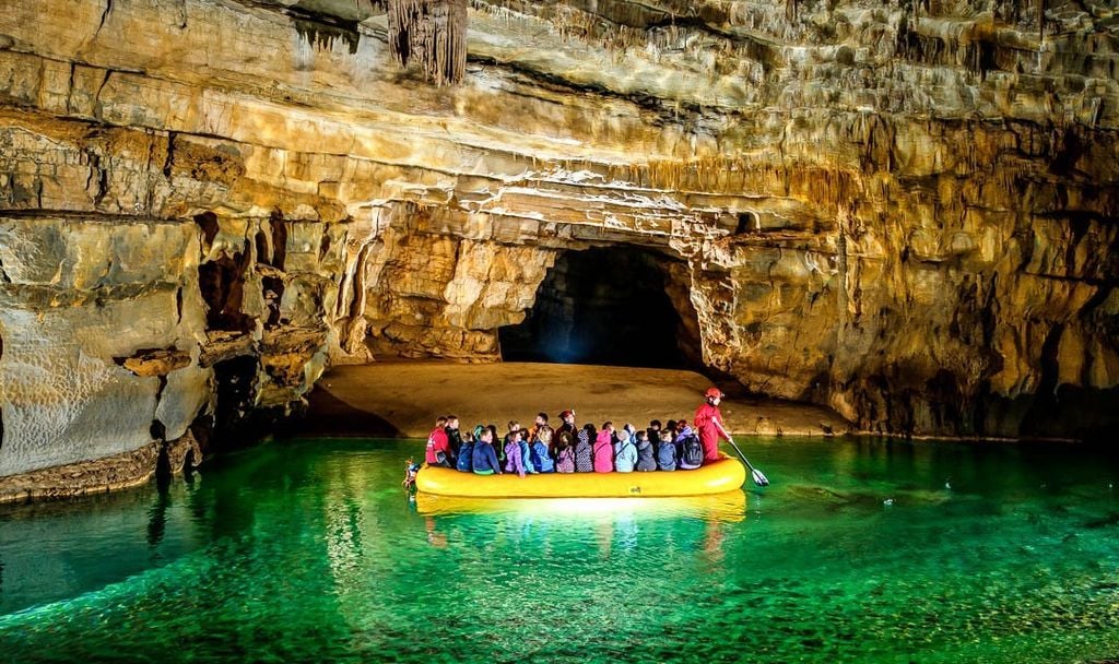 Rafters head through the caves of Slovenia, with the turquoise water shining below the karst roof.