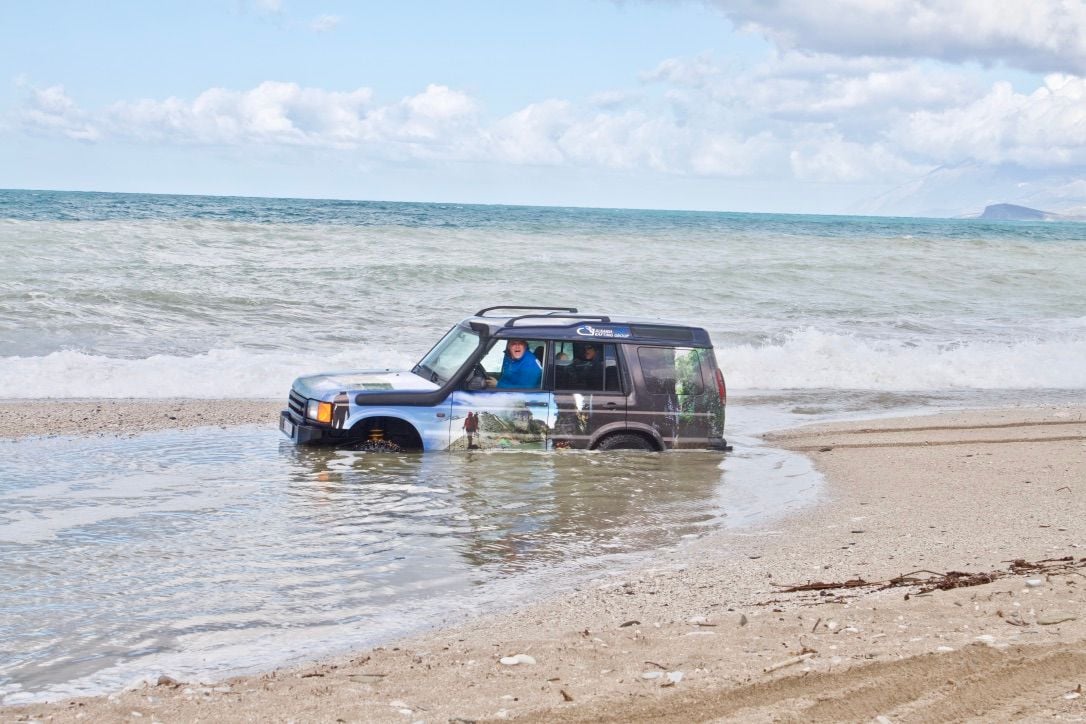 A jeep stuck in the sand on a beach in Albania
