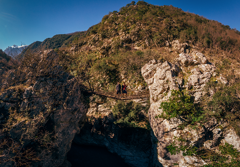 Hikers pose on a wooden bridge in Albania.