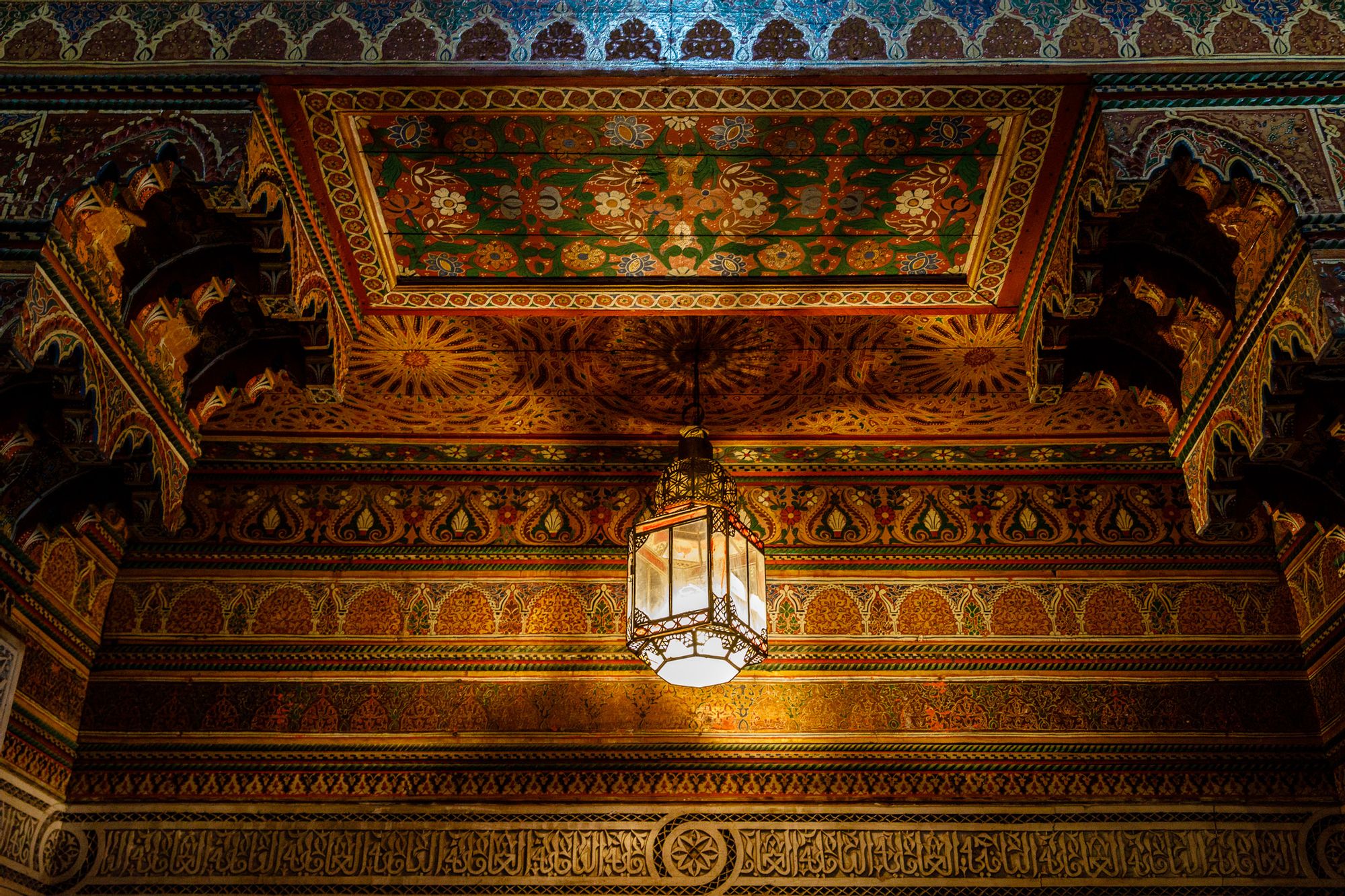 A Moroccan lamp reflects light on an ornately painted ceiling in Imlil, Morocco.