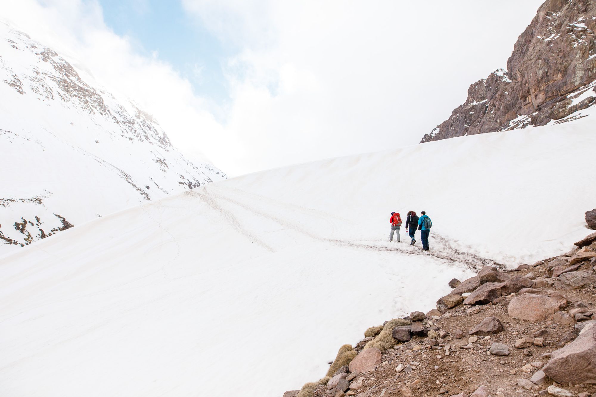 A hiking group walk across a snowy slope in the High Atlas, Morocco.