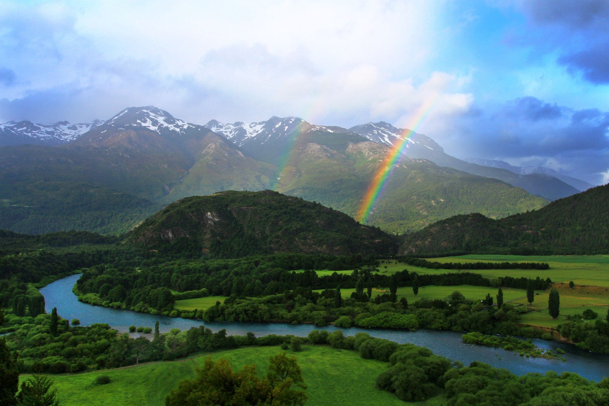 Three rainbows climb over rolling mountains at the Patagonia Rafting Lodge.