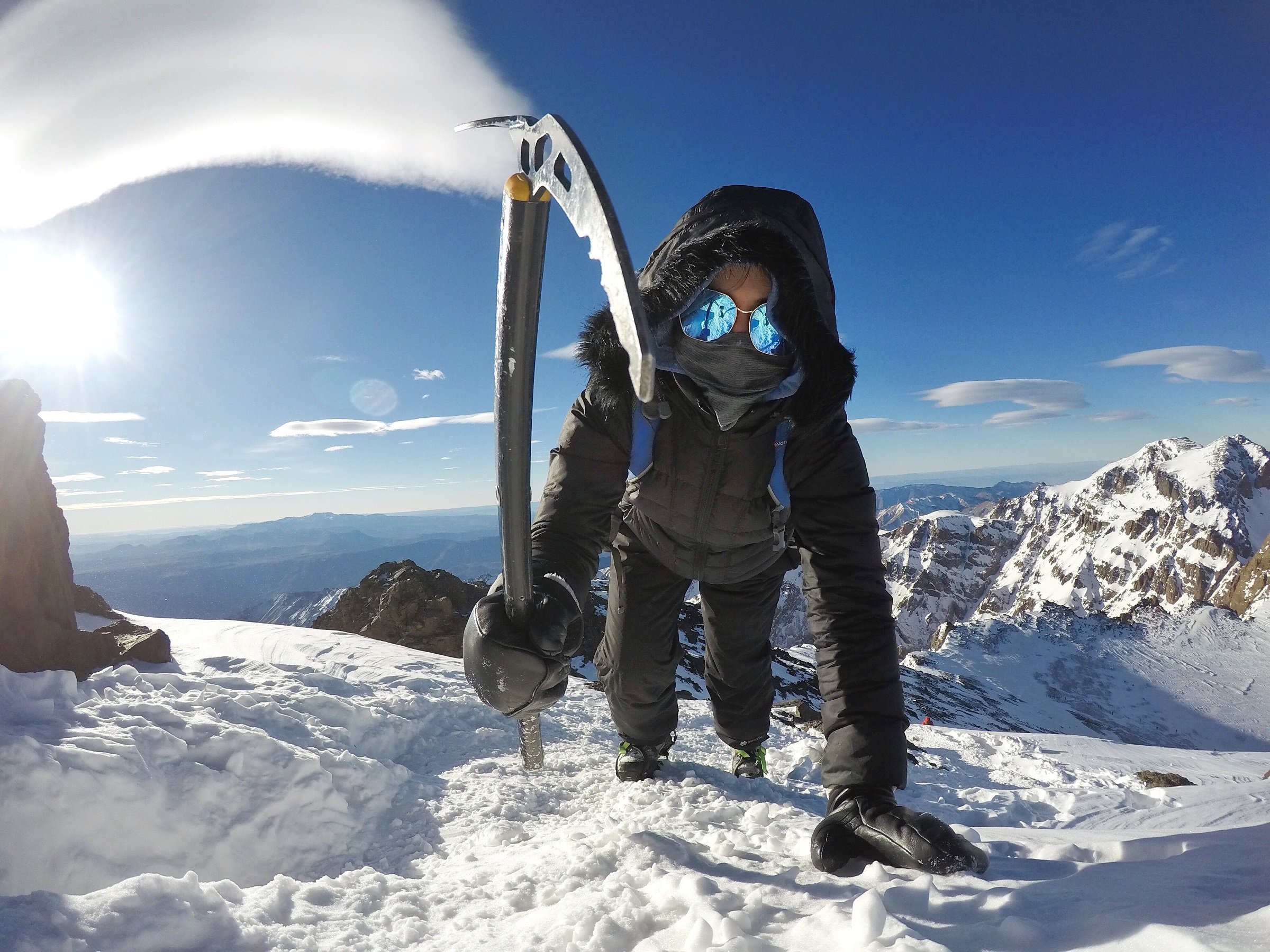 Zoe Tehrani at the top of Mount Toubkal, using an ice axe to climb