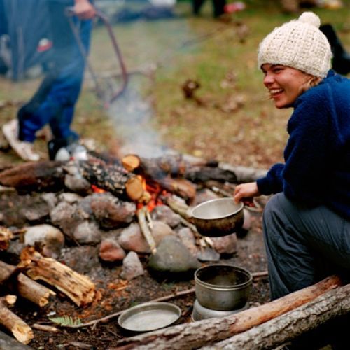 A woman sits by a campfire in Norway.