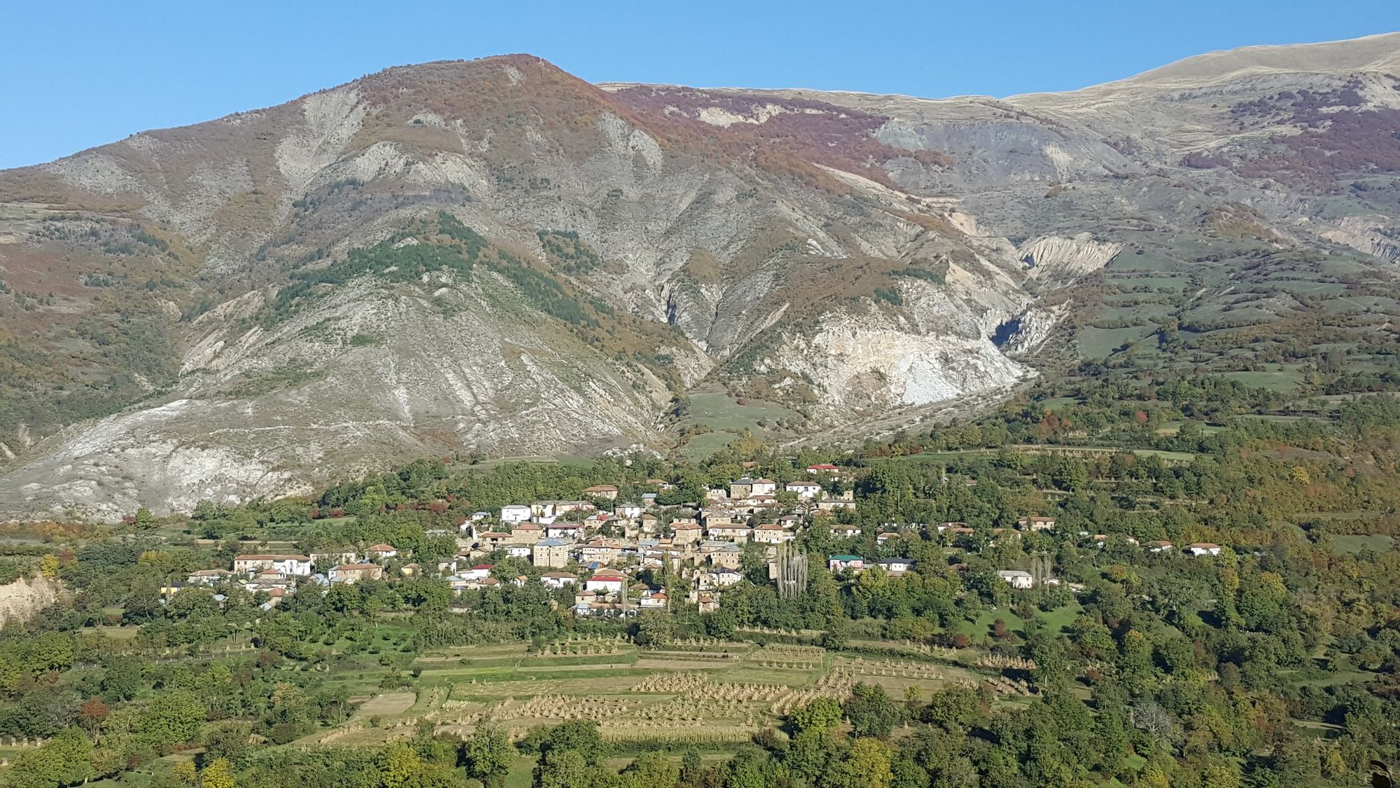 A small village in the Kosovo region, with mountains behind.