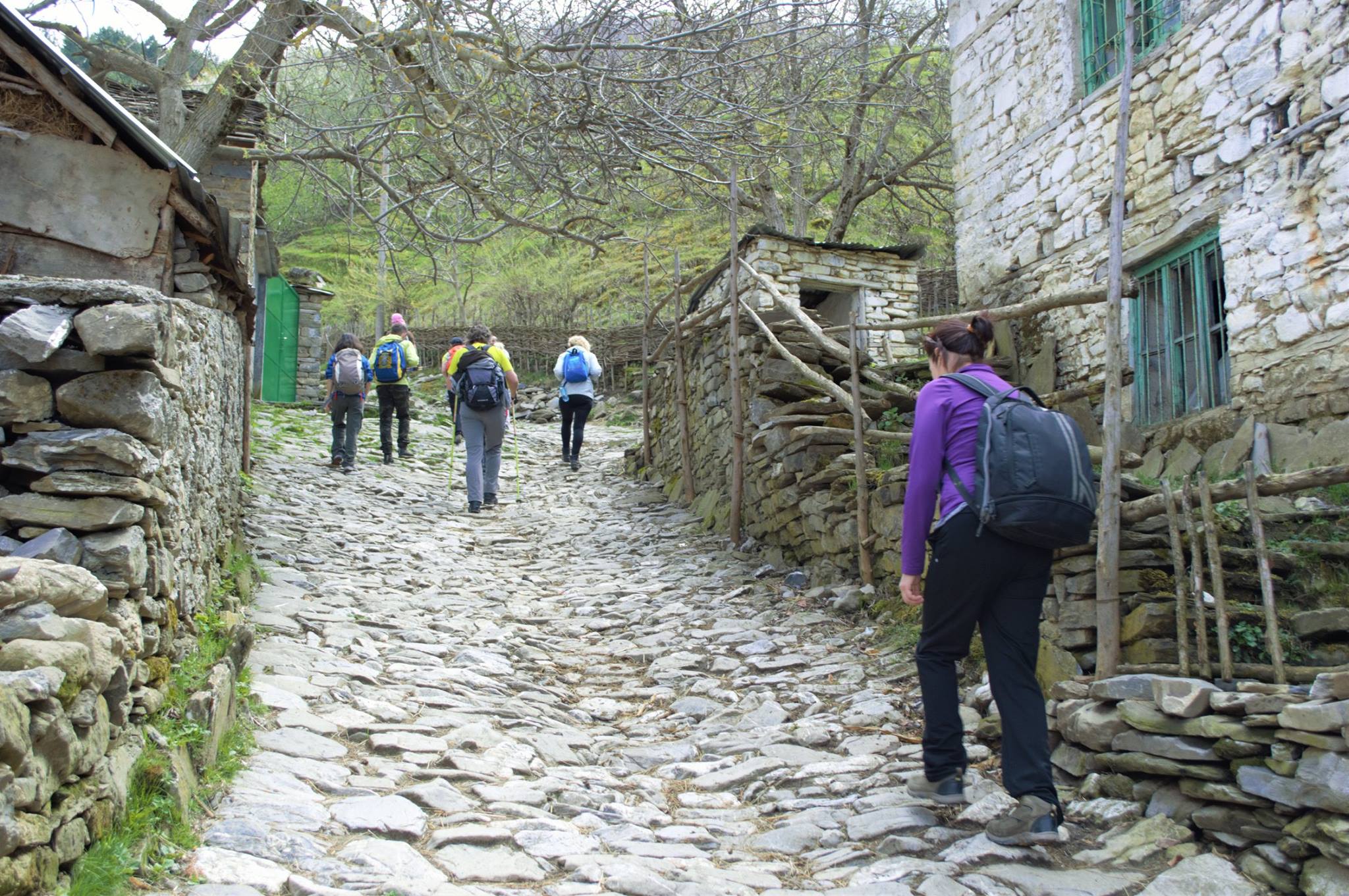 Hikers walk up the cobbled lane of a village in the Balkans