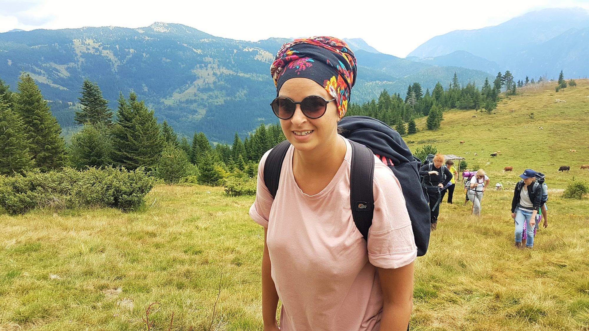 A female hiker with forest and mountains behind.