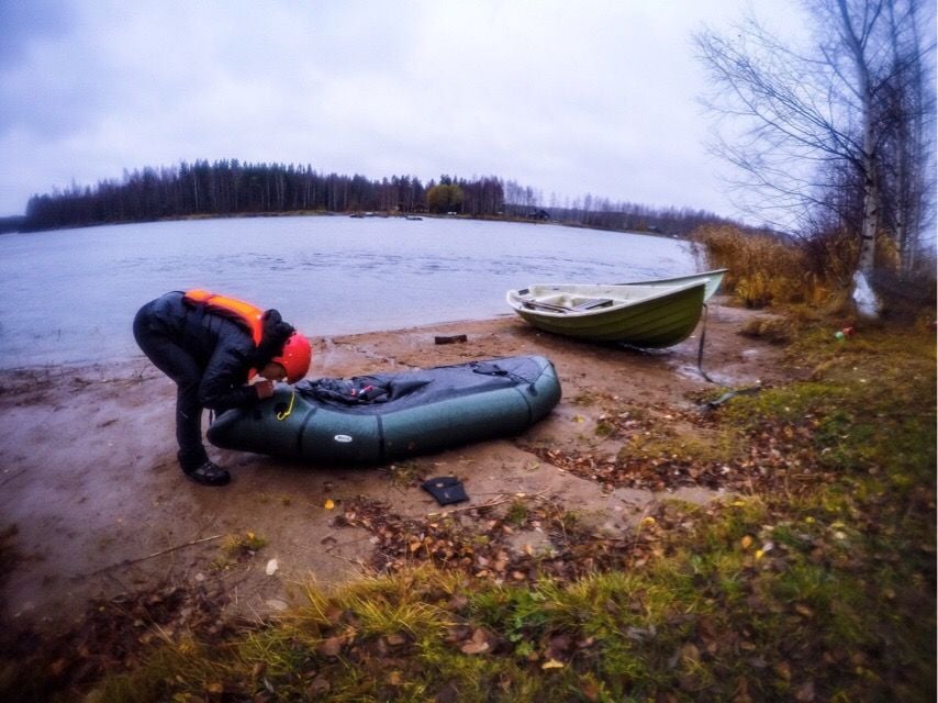 A woman inflates a packraft on the shore in Finland.