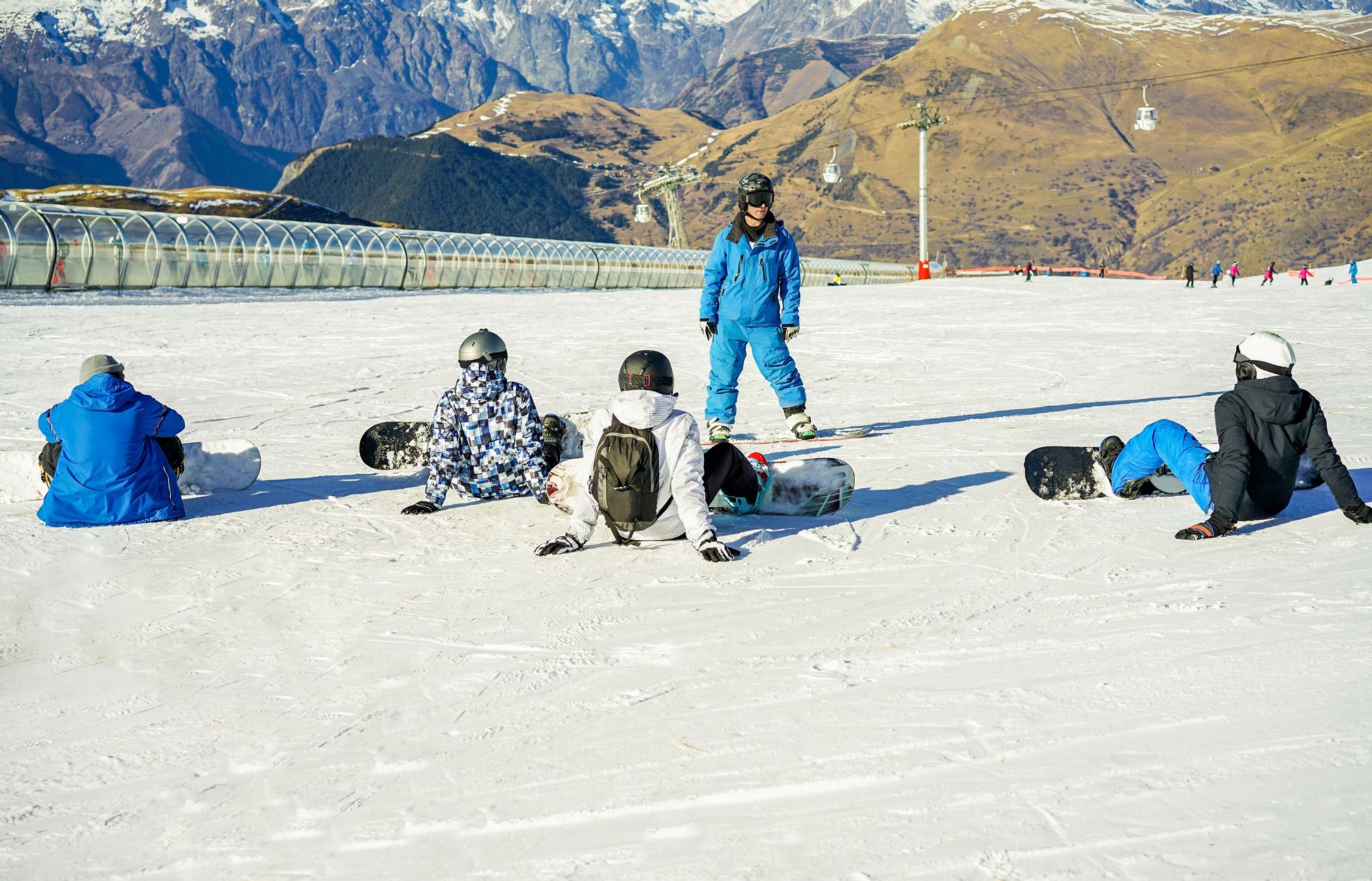 A group learn how to snowboard during a lesson in France.