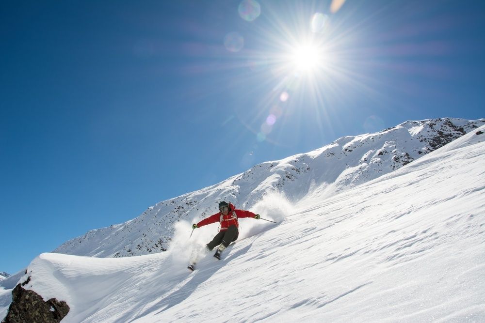 A skier going down a steep slope in the sunshine.